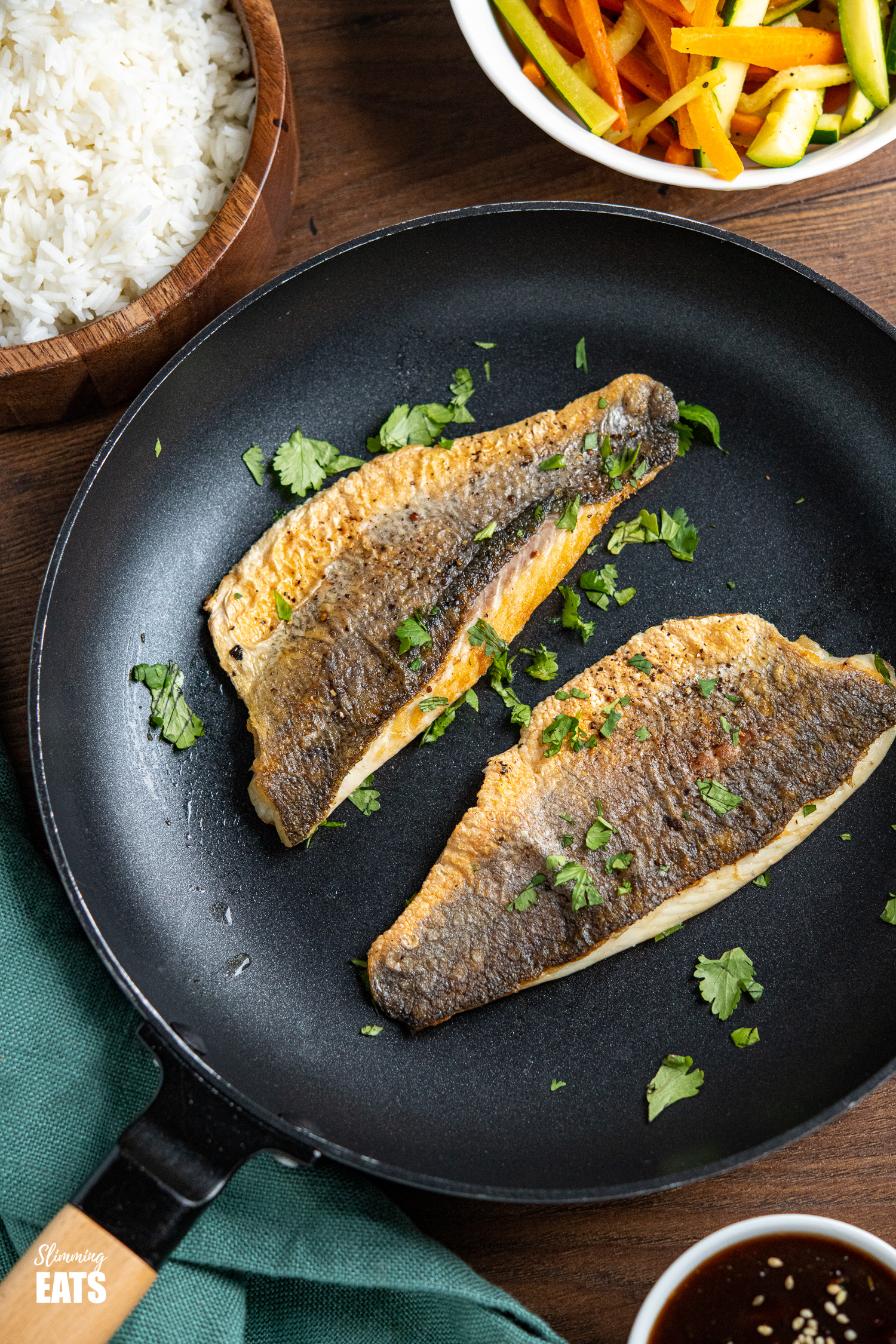 Pan-fried Sea Bass in frying pan with scattered chopped cilantro