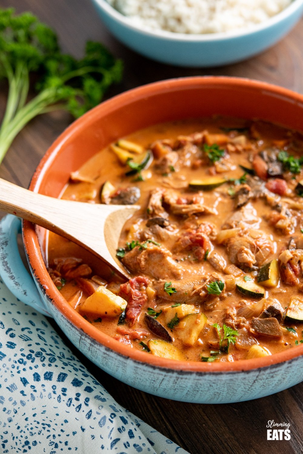 slow cooker creamy tomato and turkey casserole in ceramic blue dish with wooden spoon