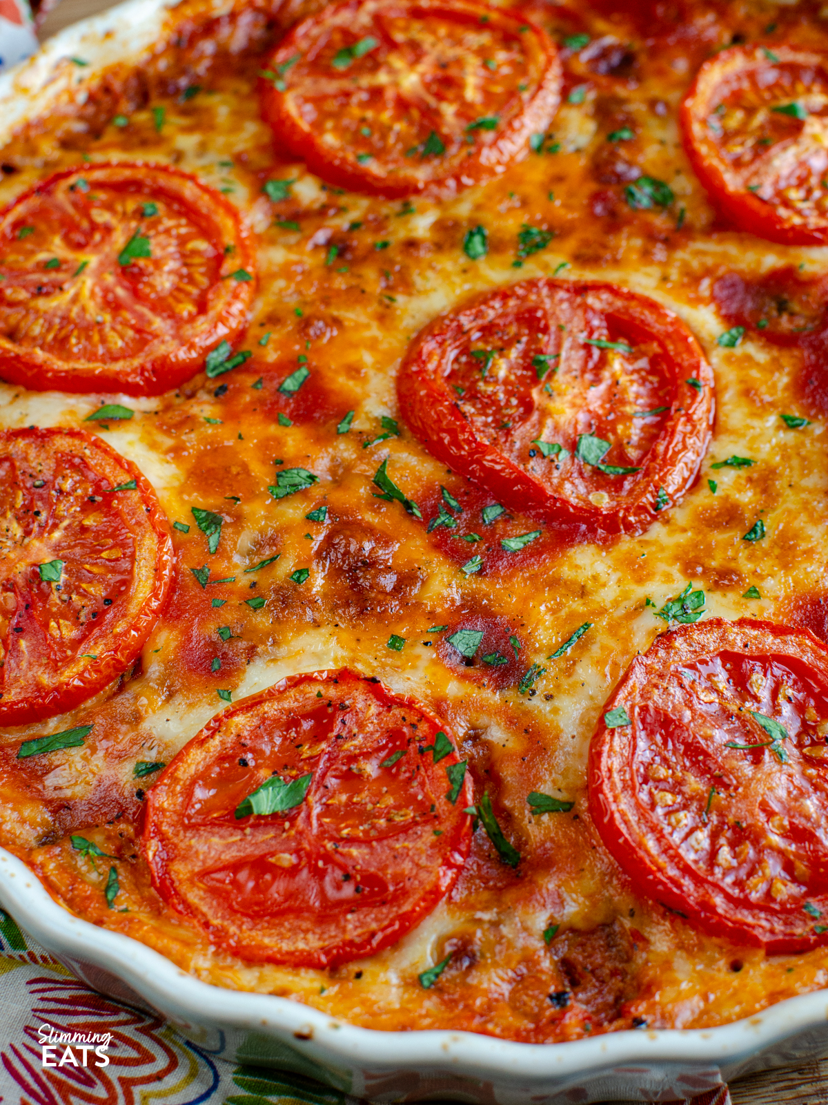 close up of cheesy tomato toppped spaghetti squash bake in a quiche ceramic dish 