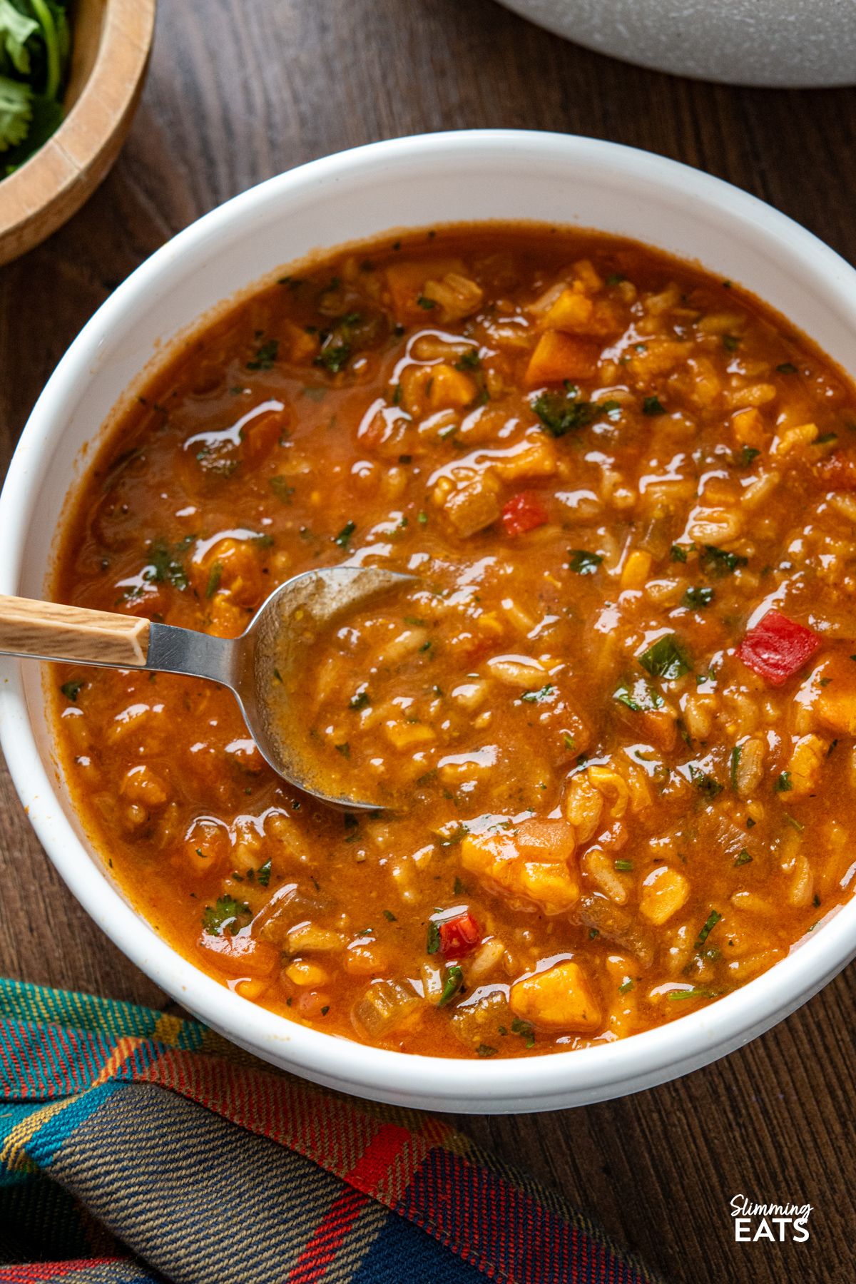 close up of portion of Spicy Sweet Potato, Vegetable and Rice Soup in a white bowl with a spoon