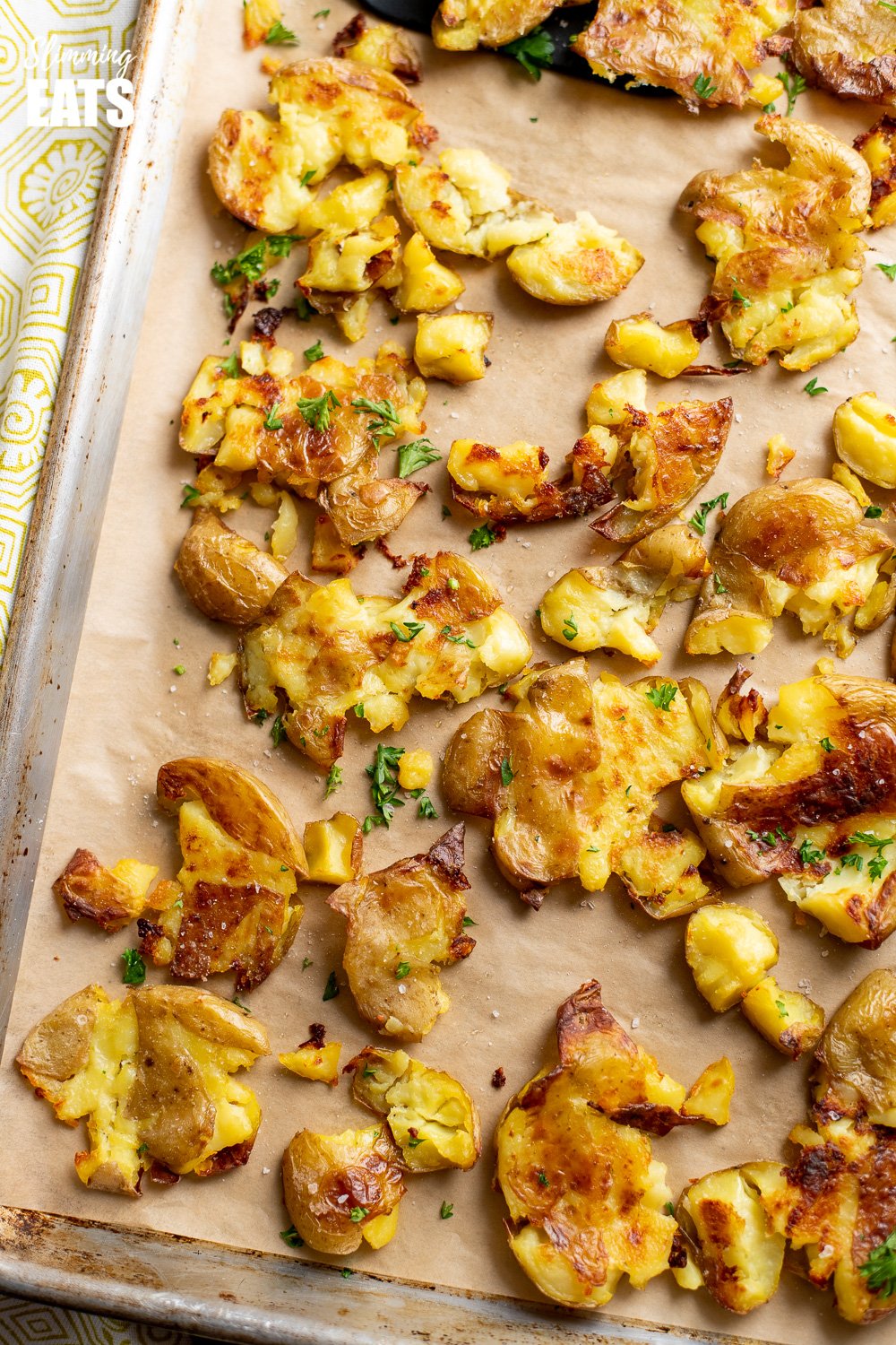 crushed roast potatoes on parchment paper lined baking tray