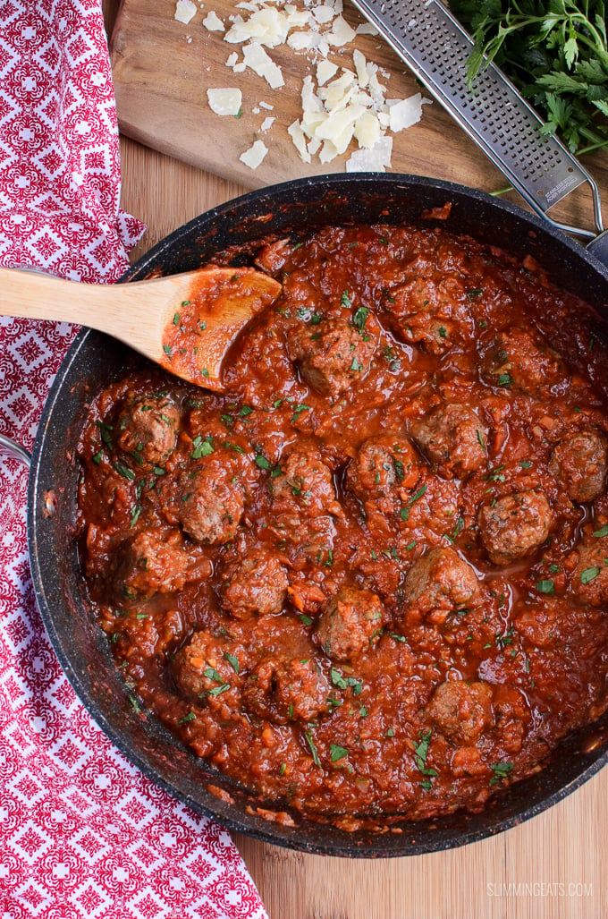 meatballs in tomato veggies sauce in a frying pan with wooden spoon