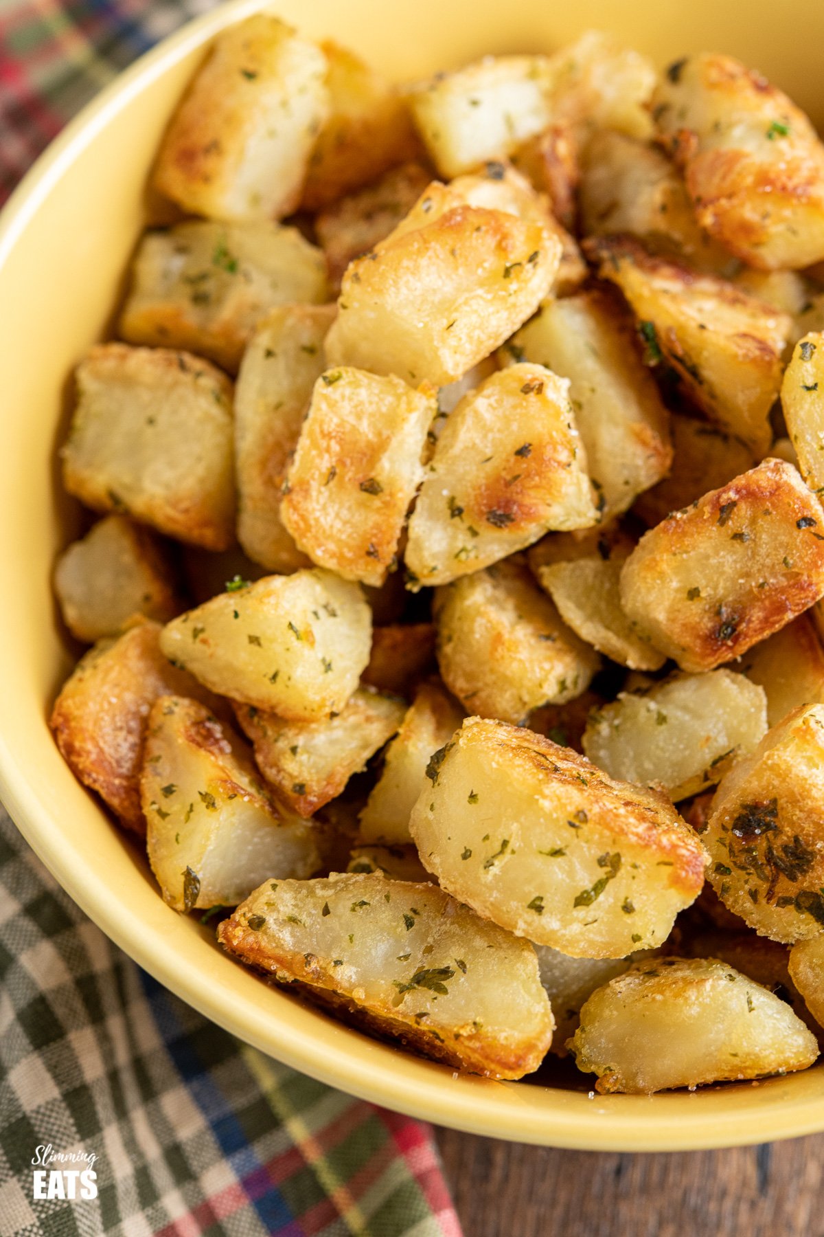 Garlic and Herb Roast Potatoes (from www.slimmingeats.com) - crispy on the outside, fluffy on the inside with the delicious flavours of garlic and herbs make these the perfect side for a variety of main meals. #glutenfree #dairyfree #vegan #vegetarian #slimmingworld #weightwatchers Garlic and Herb Roast Potatoes in yellow bowl
