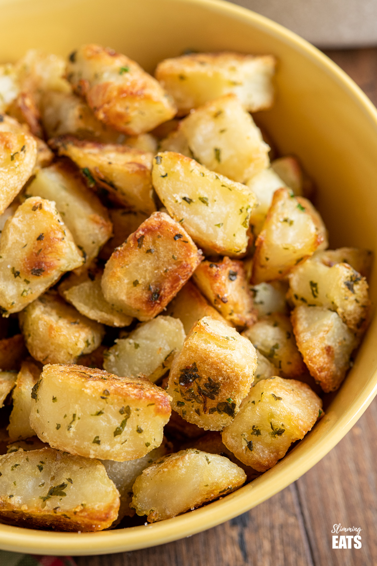 close up of Garlic and Herb Roasted Potatoes in a yellow bowl