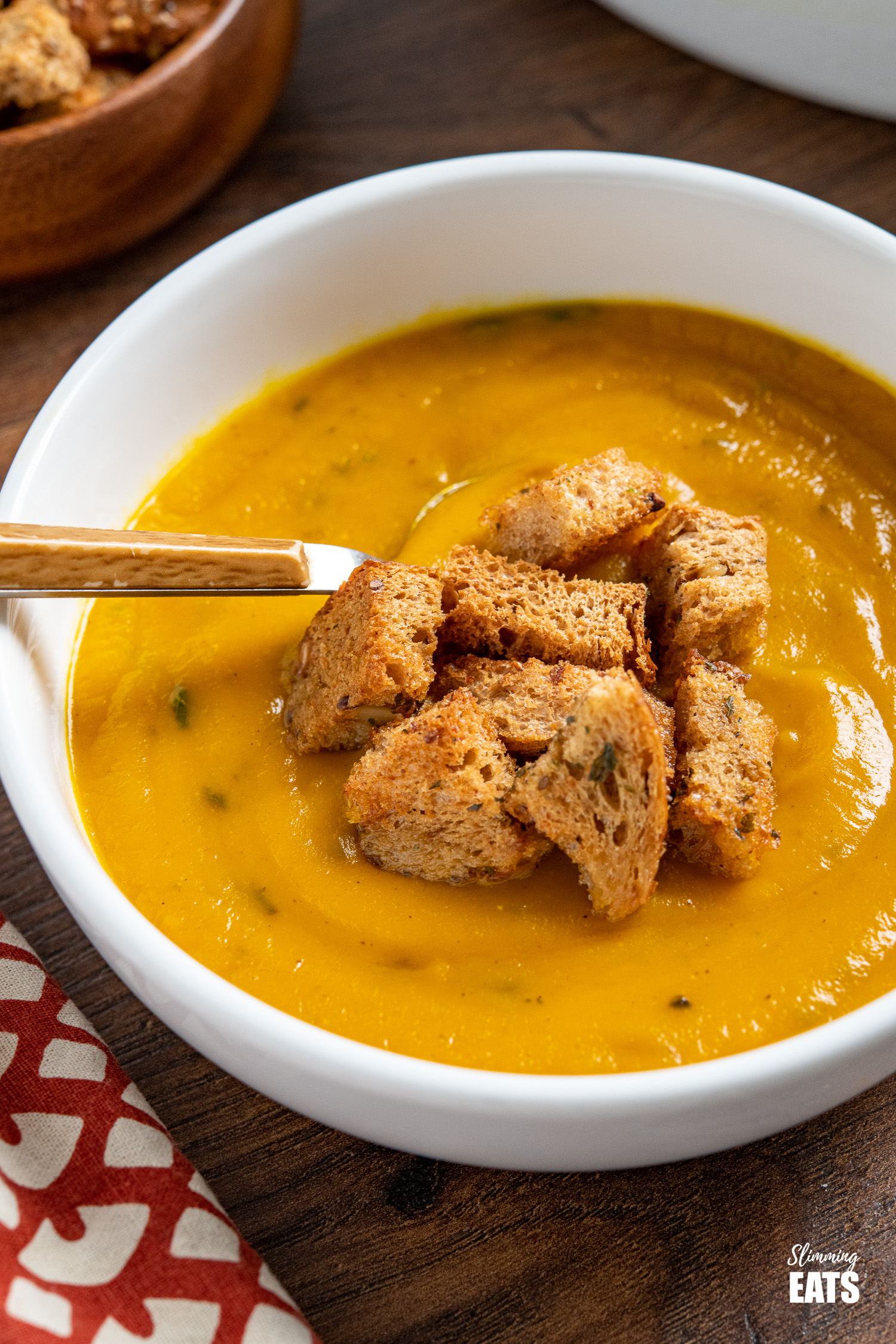 close up of Butternut Squash soup with Garlic Herb Croutons with wooden handled spoon