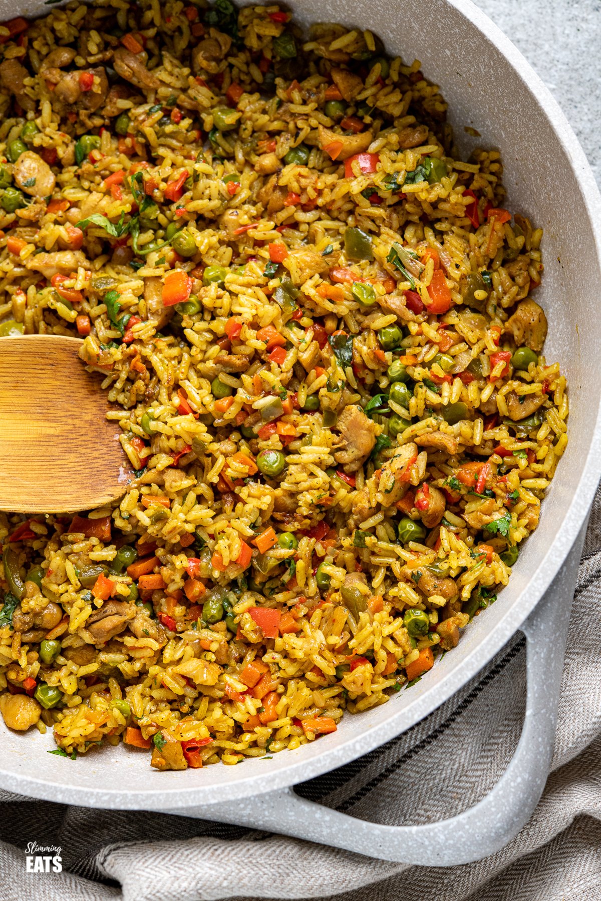 One Pot Coconut Chicken Curry Rice - a super easy all in one pan family-friendly meal with pieces of tender chicken thigh and vegetables with delicious coconut and curry flavours. Coconut Chicken Curry Rice in frying pan with wooden spoon