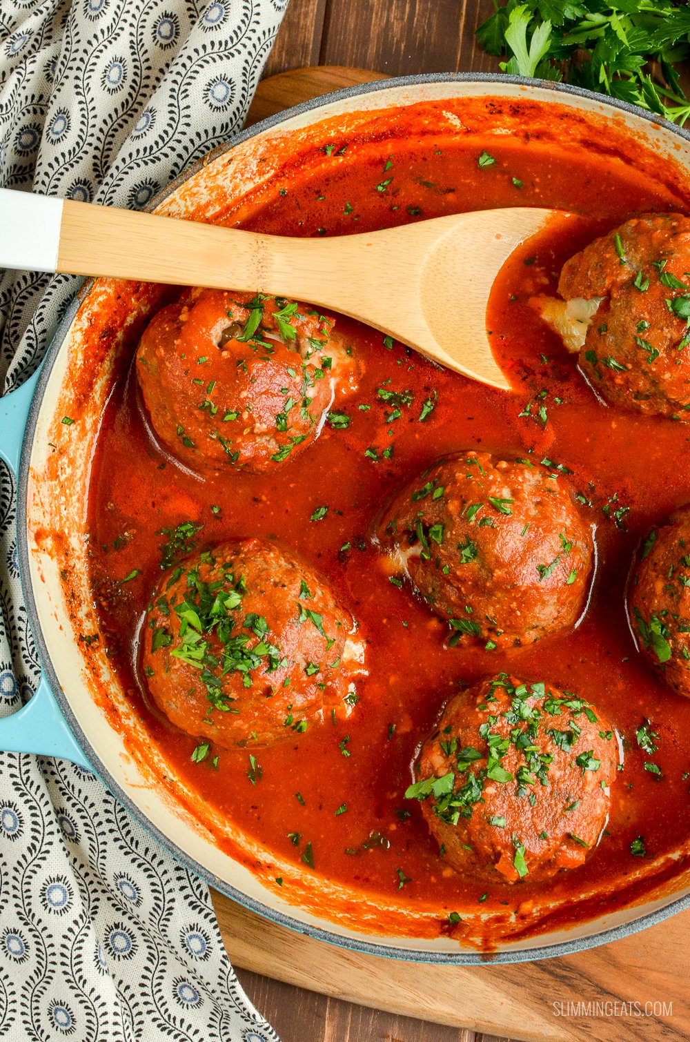 mega stuffed meatballs in tomato sauce in cast iron pan with wooden spoon