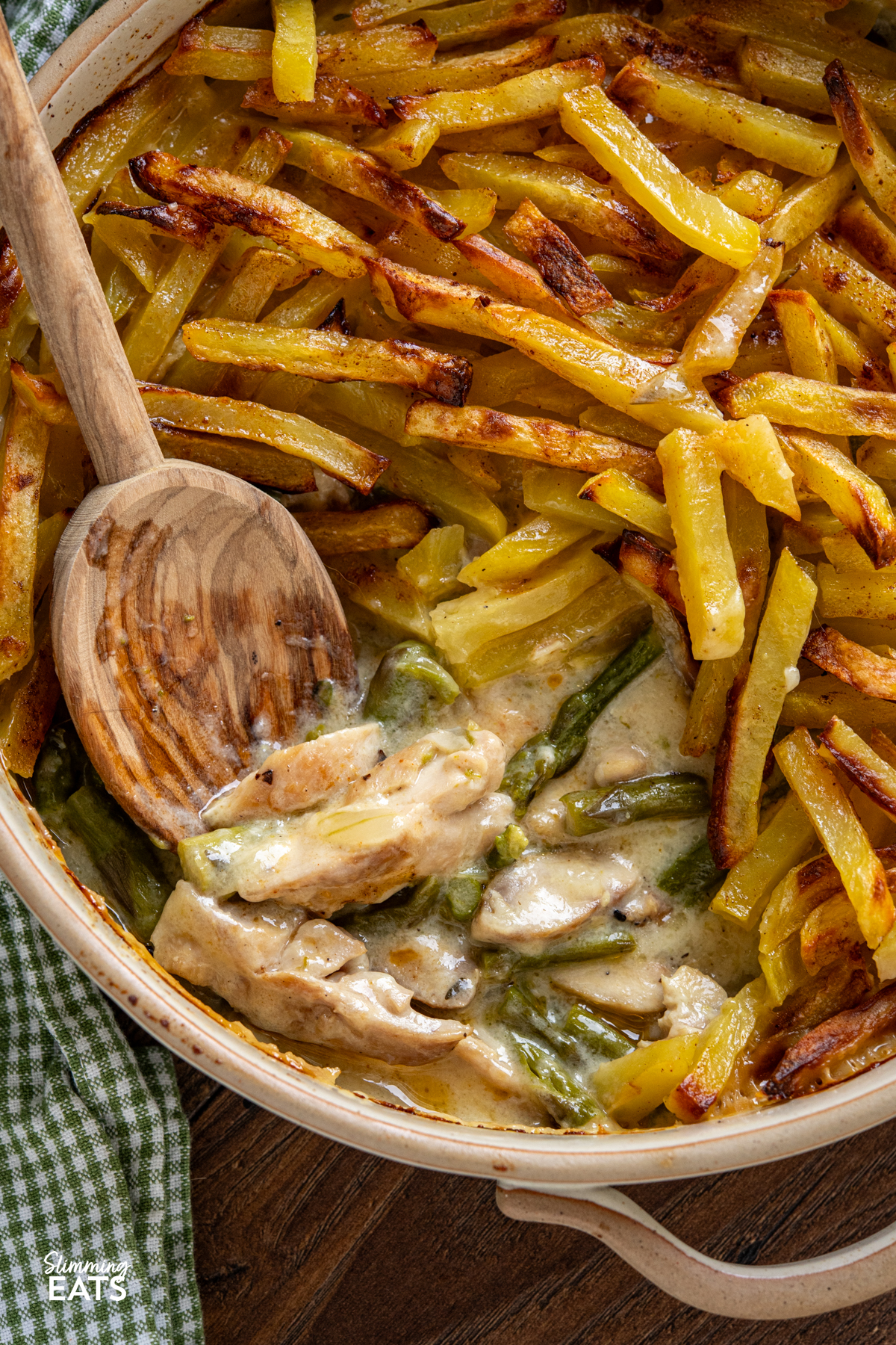 This Chicken and Asparagus Pie with Crispy Potatoes has a creamy, comforting filling topped with golden crispy potatoes for a delicious twist on a classic pie. close up of Crispy Potato Topped Chicken and Asparagus Pie in ceramic oven dish with two handles