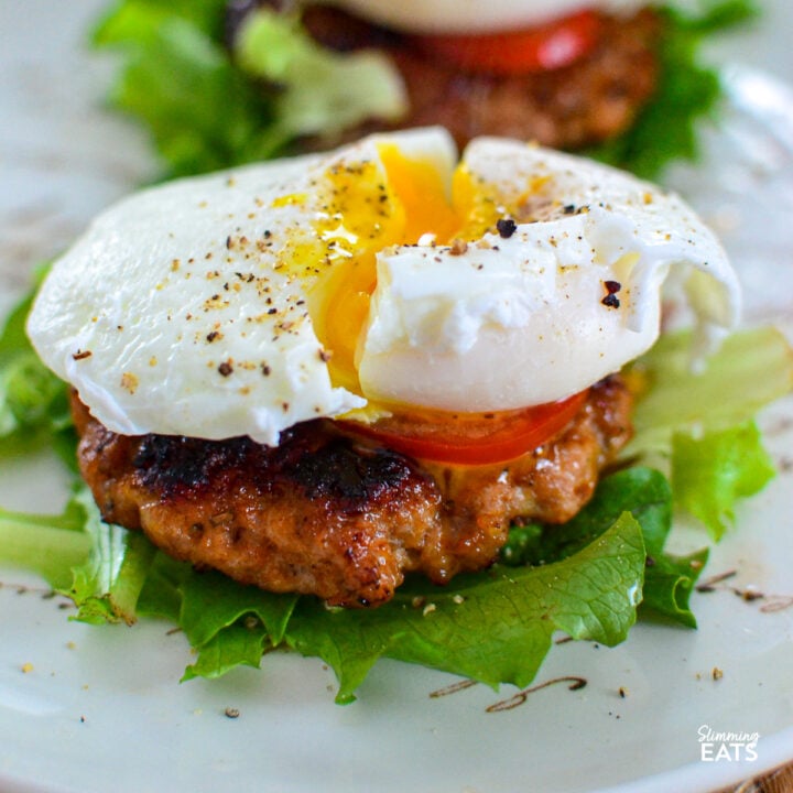 Homemade sausage patties over a bed of lettuce, topped with tomato and a poached egg, seasoned with salt and black pepper.