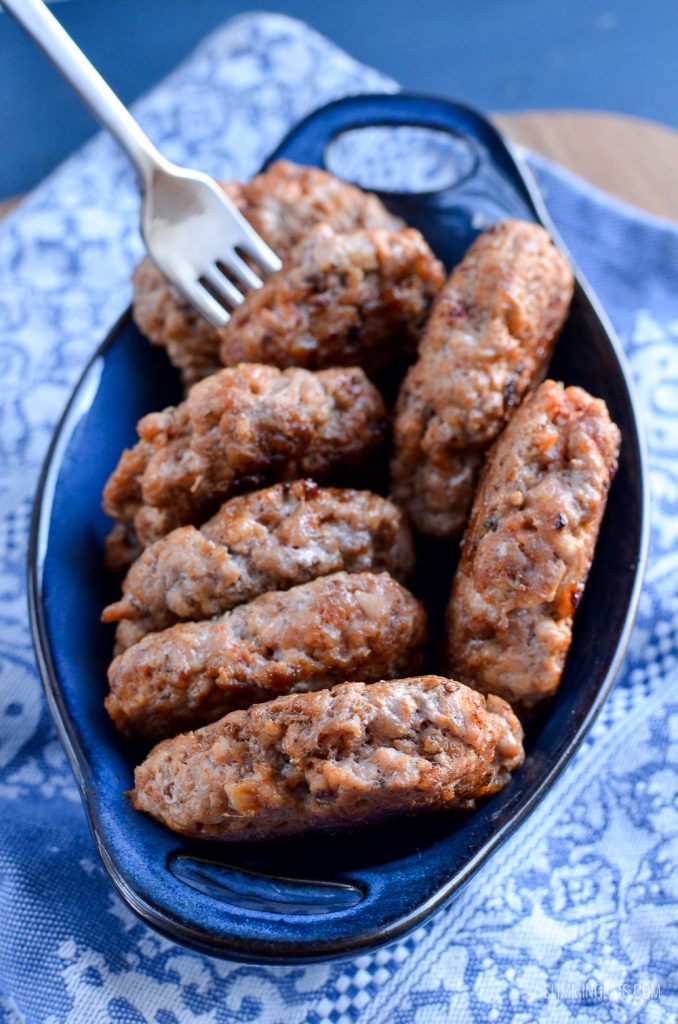 homemade pork sausage patties in a small blue ceramic dish with two handles, one pattie pierced with a fork
