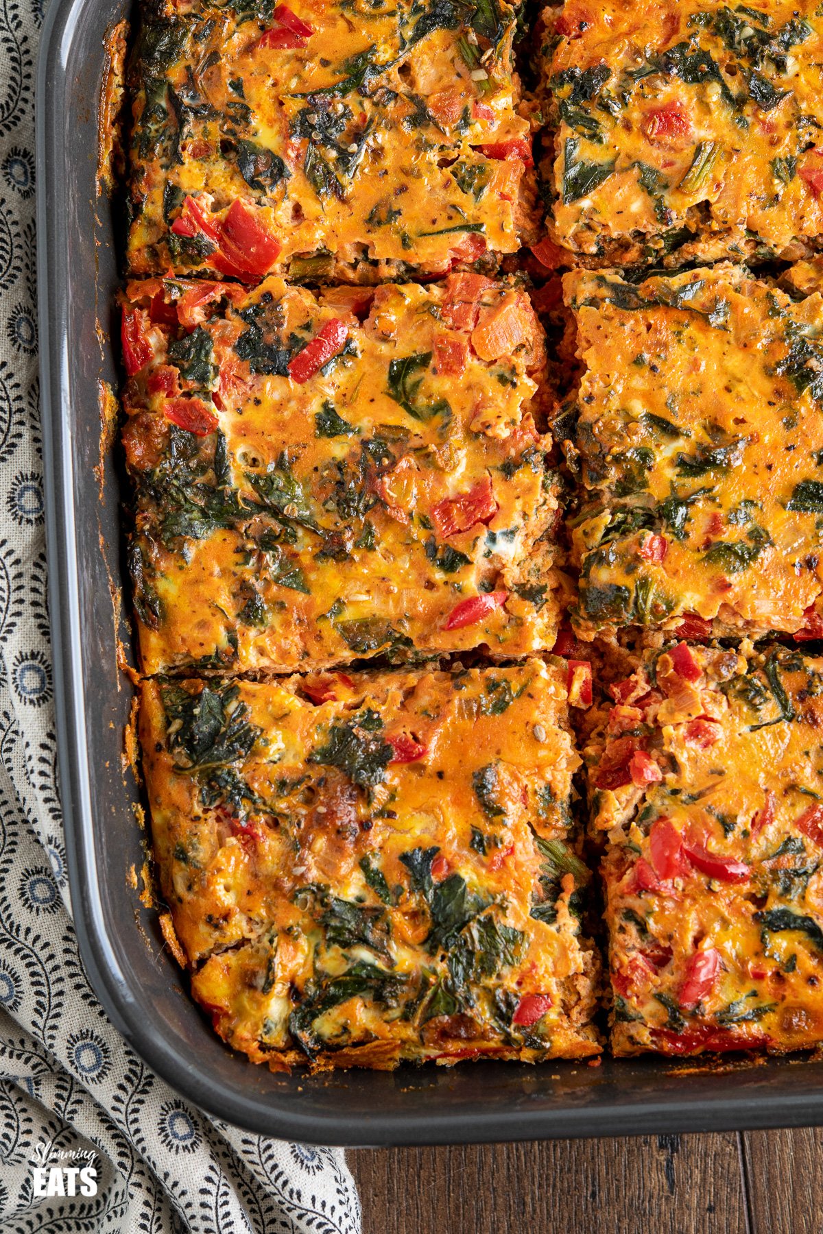 sliced Breakfast Layered Crustless Quiche in dark grey baking dish 