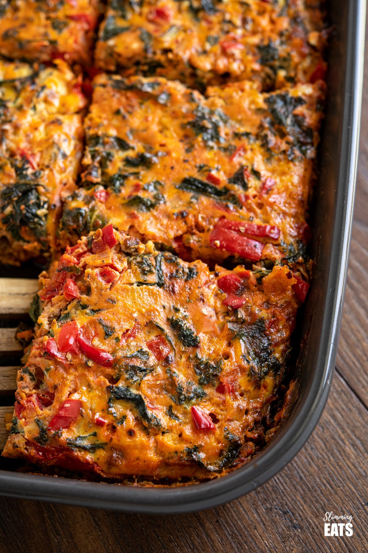 close up of sliced Breakfast Layered Crustless Quiche in dark grey baking dish