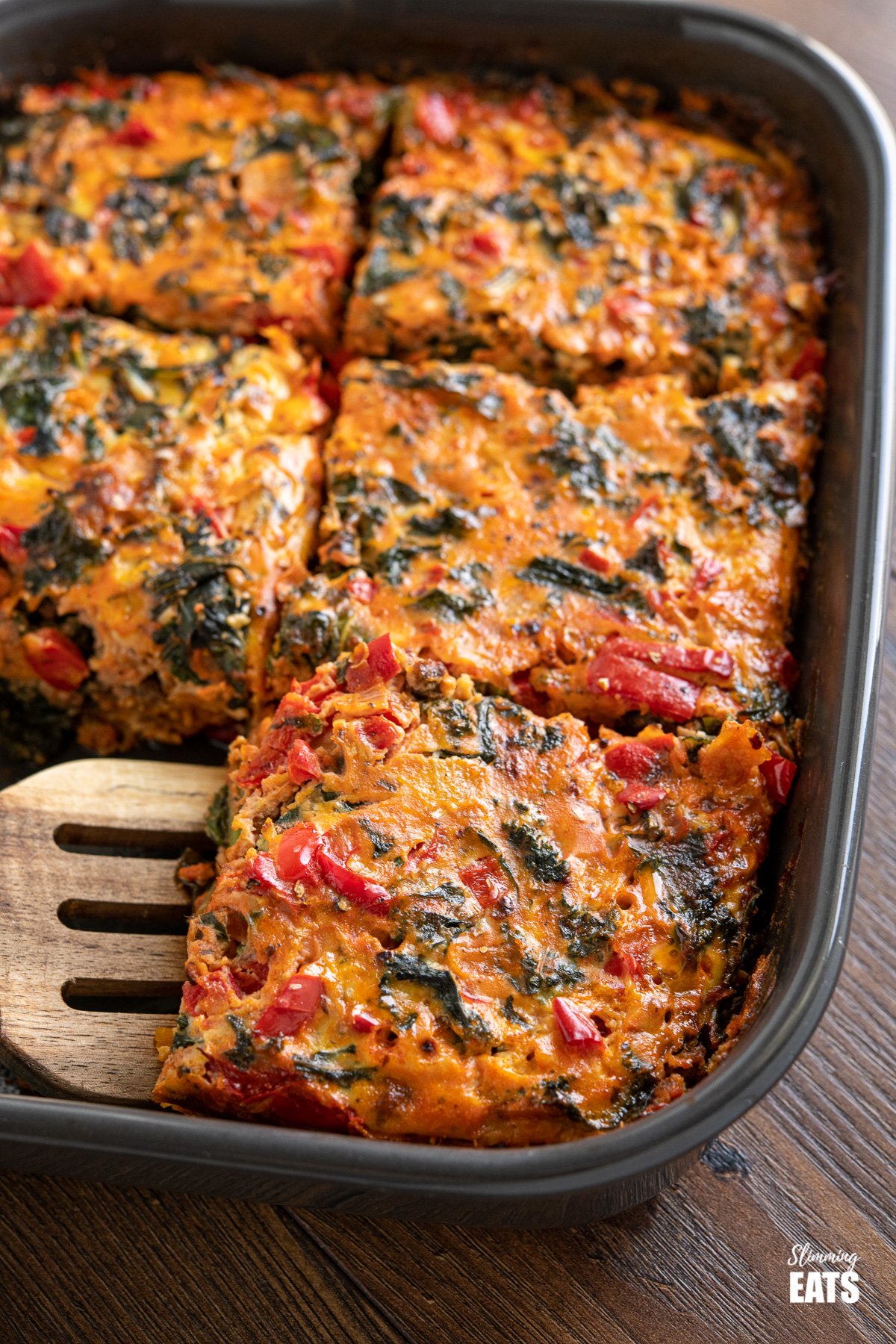 sliced Breakfast Layered Crustless Quiche in dark grey baking dish