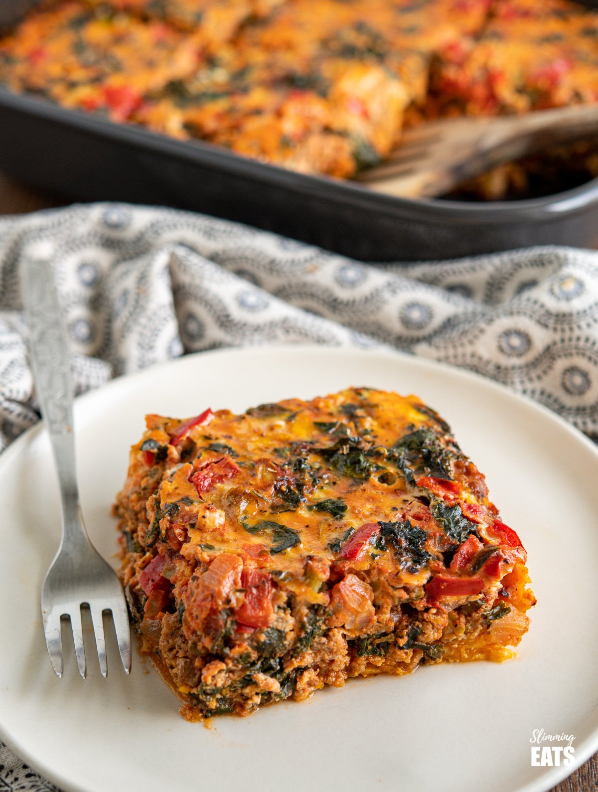 slice of Breakfast Layered Crustless Quiche on cream plate with fork