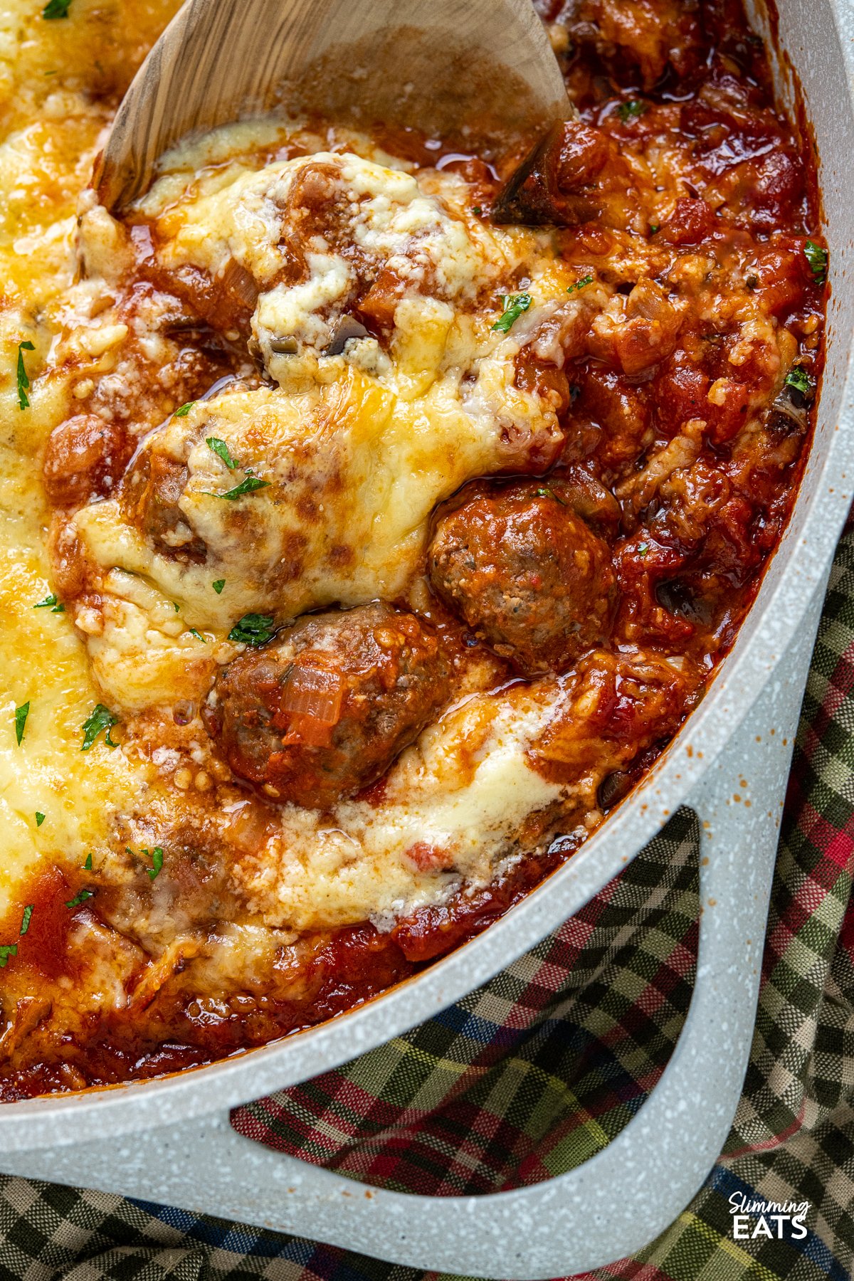 Indulge in the tantalizing flavors of the Mediterranean with this delicious creation of Moussaka Meatballs - tender seasoned lamb meatballs in a rich tomato sauce topped with a light creamy Bechamel sauce. Get ready to embark on a culinary journey that will transport your taste buds straight to the sun-soaked shores of Greece! close up of Greek Moussaka Meatballs in a non stick ceramic casserole dish