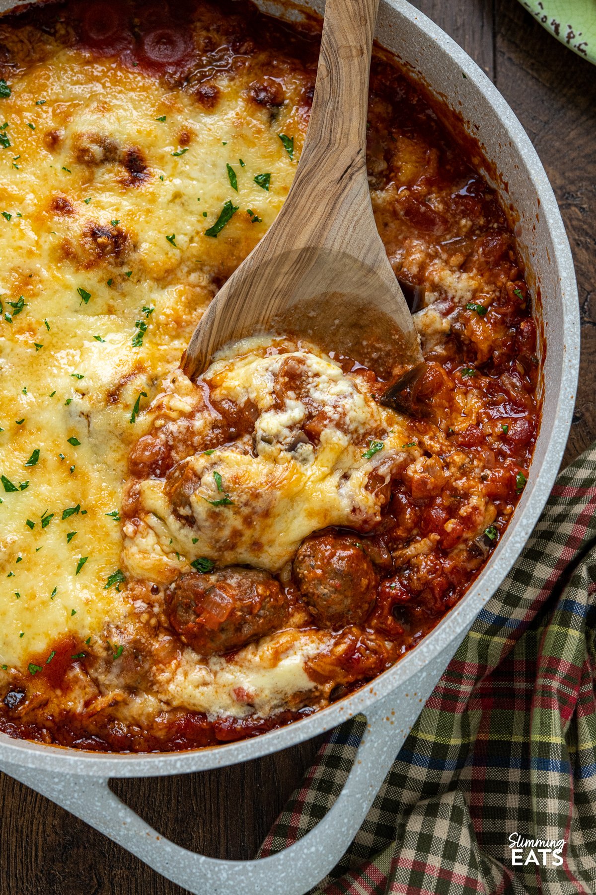 Indulge in the tantalizing flavors of the Mediterranean with this delicious creation of Moussaka Meatballs - tender seasoned lamb meatballs in a rich tomato sauce topped with a light creamy Bechamel sauce. Get ready to embark on a culinary journey that will transport your taste buds straight to the sun-soaked shores of Greece! close up of Greek Moussaka Meatballs in a non stick ceramic casserole dish