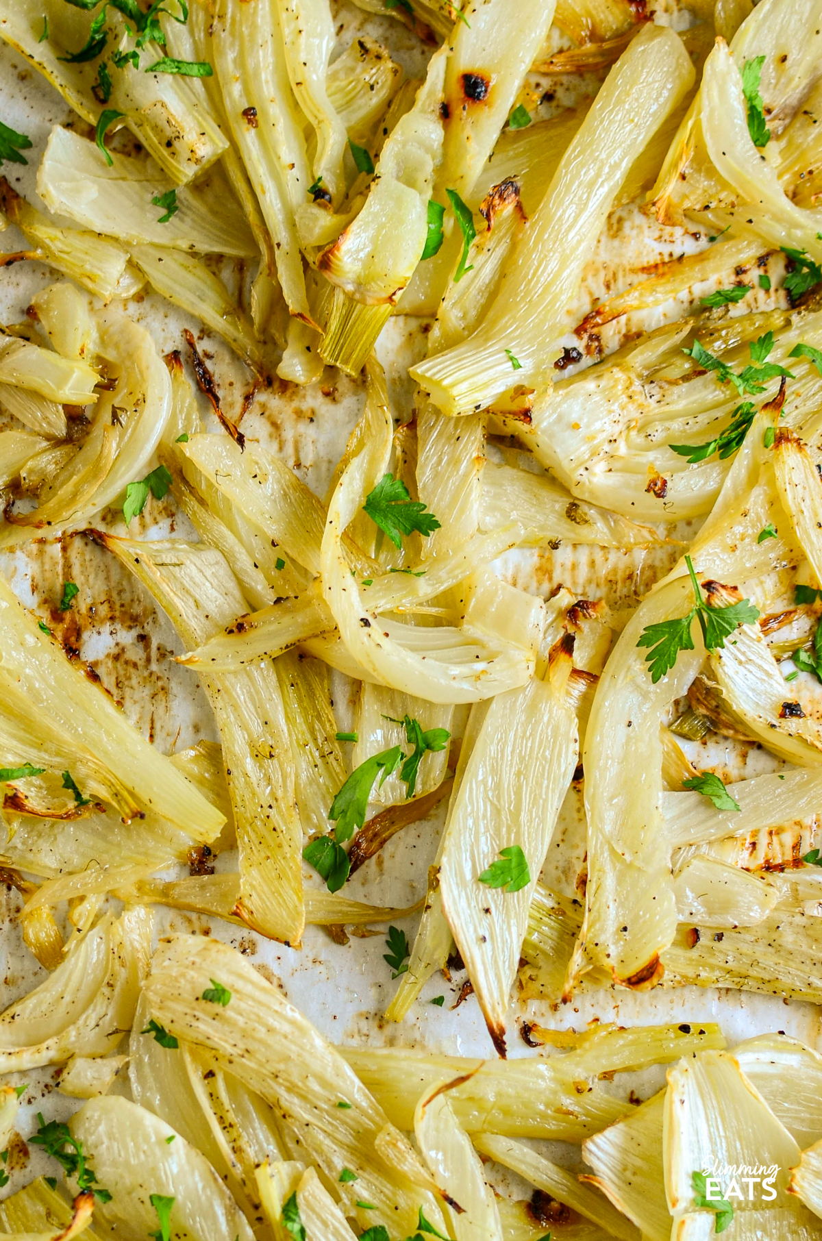 close up of lemon garlic roasted fennel on a parchment lined tray