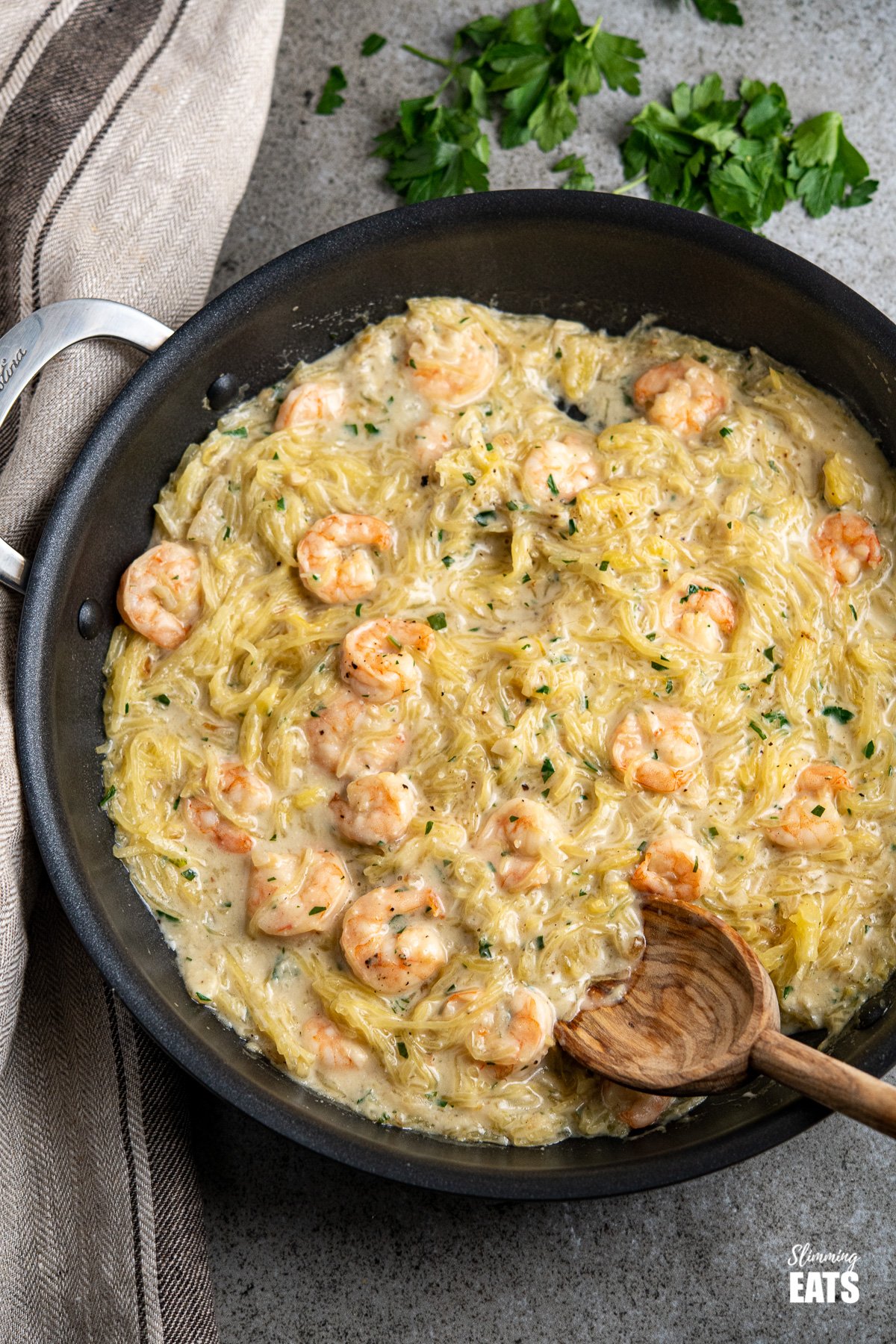 Shrimp Spaghetti Squash Alfredo - delicious shrimp in a creamy dairy free Alfredo sauce with low carb spaghetti squash. A perfect pasta alternative dish. #dairyfree #lowcarb #slimmingworld #weightwatchers Shrimp Spaghetti Squash Alfredo in a black frying pan with scattered parsley above