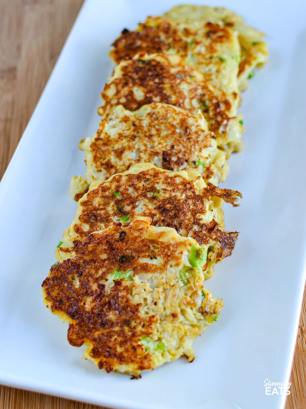 cauliflower spring onion fritters  on a white rectangle plate