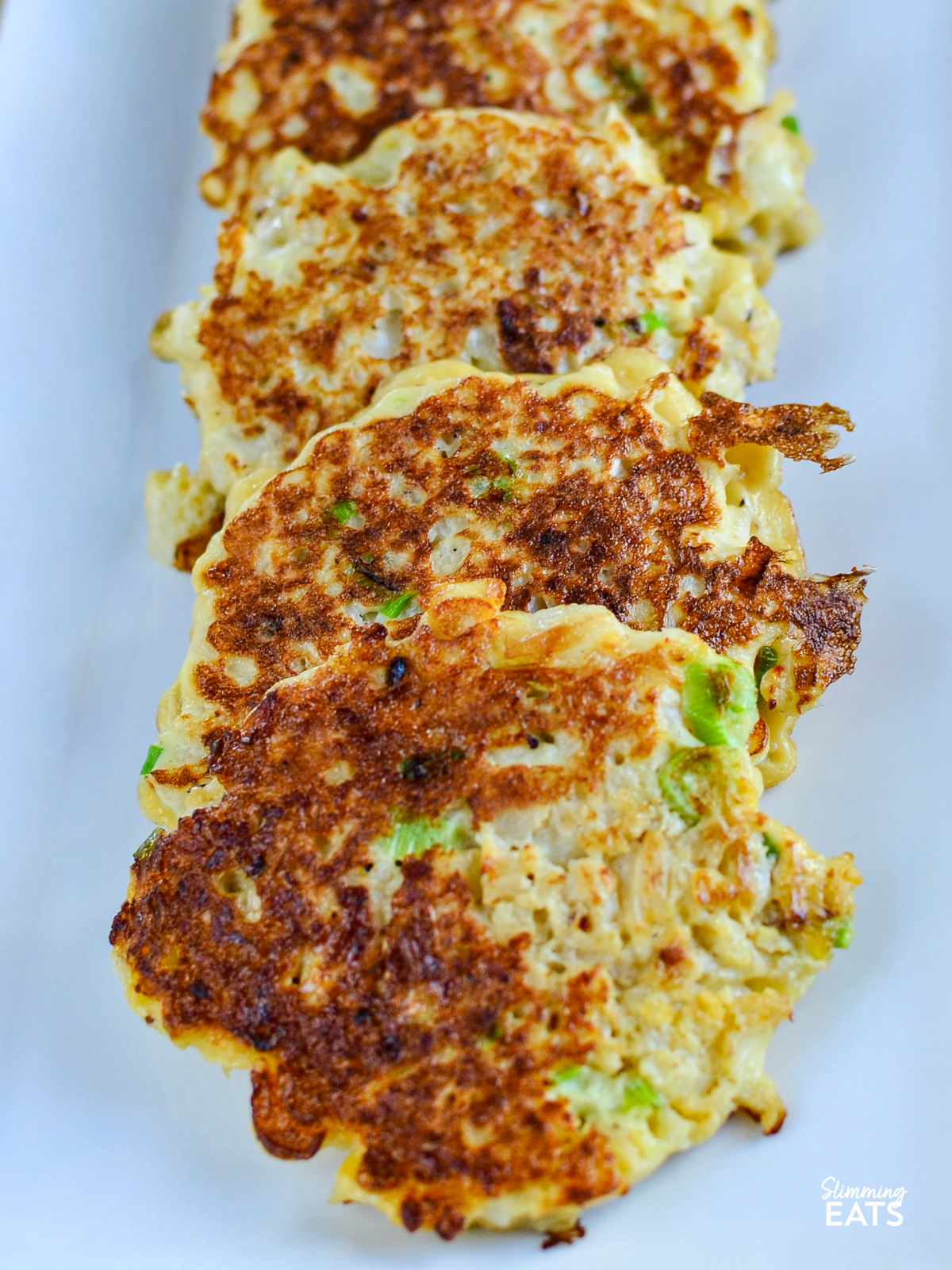 cauliflower spring onion fritters  on a white rectangle plate