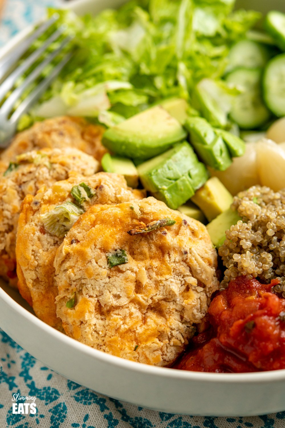 close up of Cheddar Butter Bean Bites in cream bowl with quinoa, cucumber, lettuce, salsa, avocado, beets and picked onions