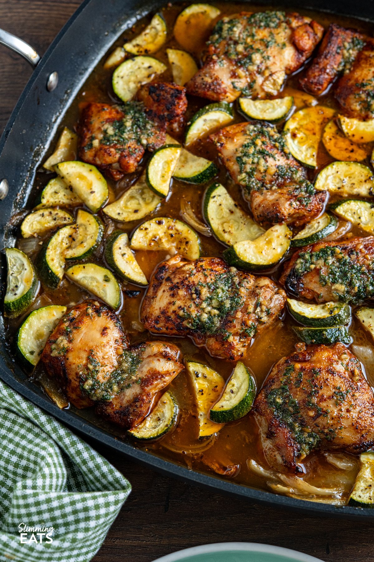 This Lemon Garlic Chicken and Zucchini Bake is an easy, delicious meal. Juicy chicken is nestled in a zesty lemon and garlic butter sauce with tender seasoned zucchini. close up of Garlic Lemon Chicken and Zucchini Bake in a all-clad square skillet