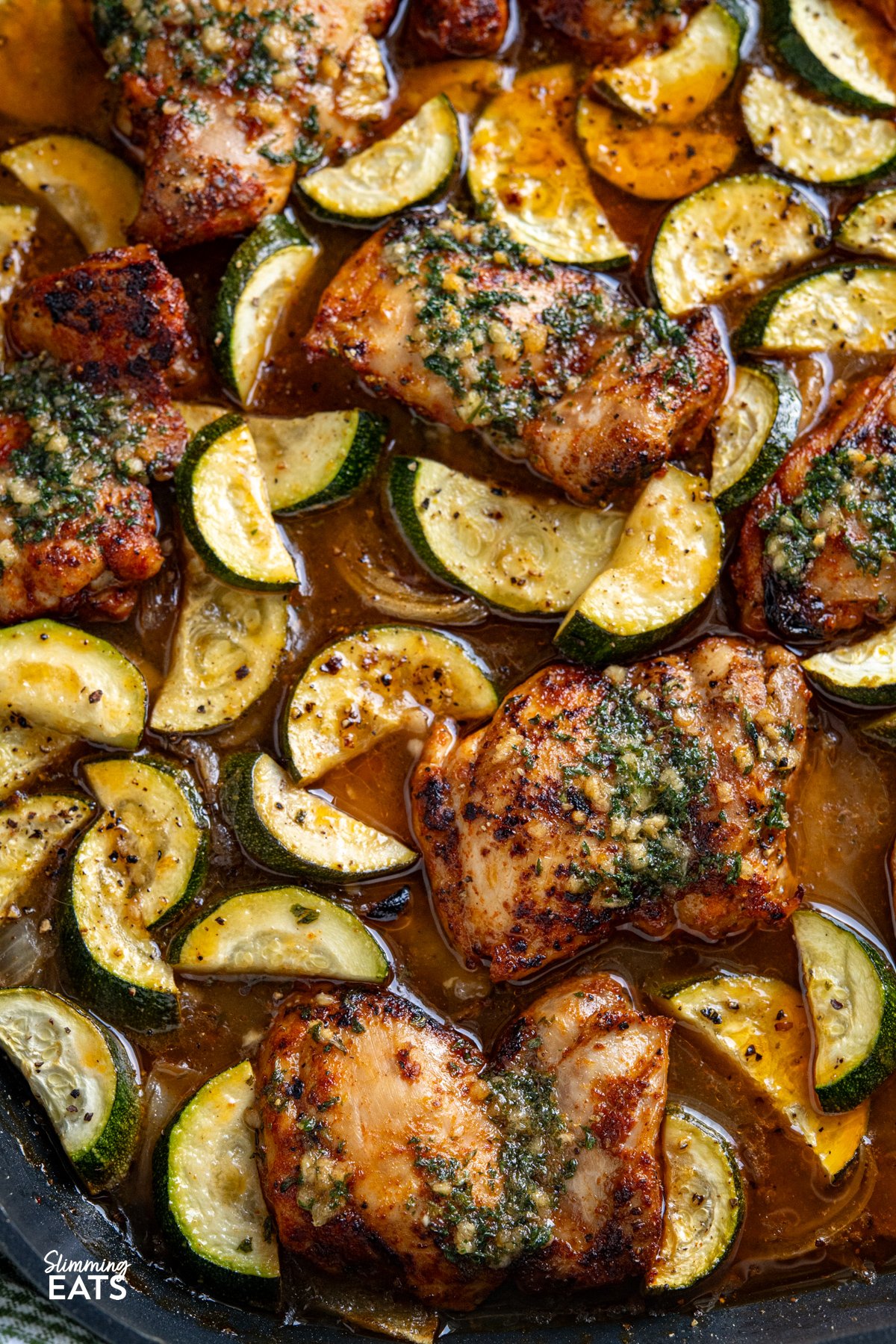 This Lemon Garlic Chicken and Zucchini Bake is an easy, delicious meal. Juicy chicken is nestled in a zesty lemon and garlic butter sauce with tender seasoned zucchini. close up of Garlic Lemon Chicken and Zucchini Bake in a all-clad square skillet