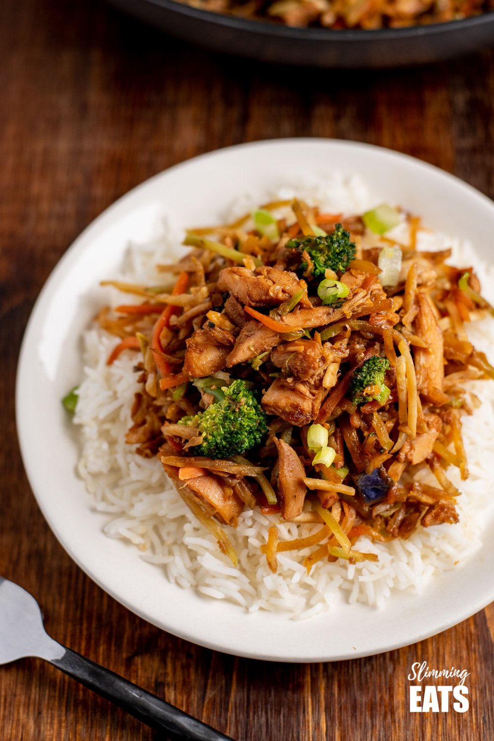 close up of orange and ginger turkey stir fry with rice on white plate