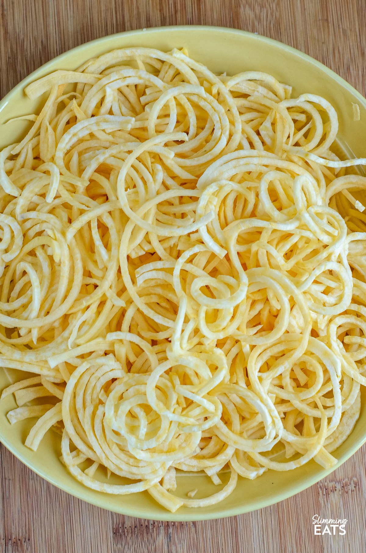 unseasoned spiralized swede fries in a yellow bowl