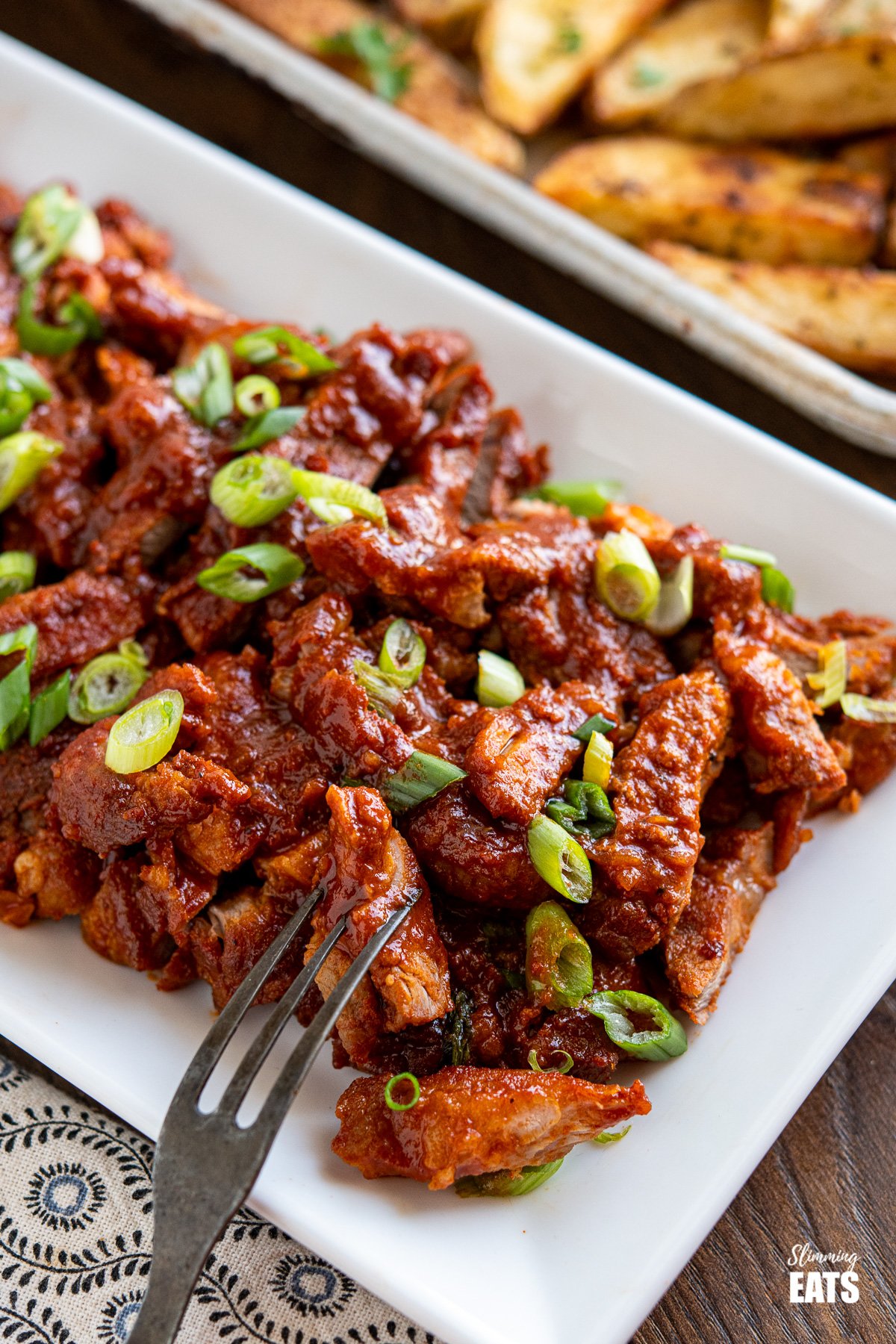 close up of stove top bbq pork on white plate with fork