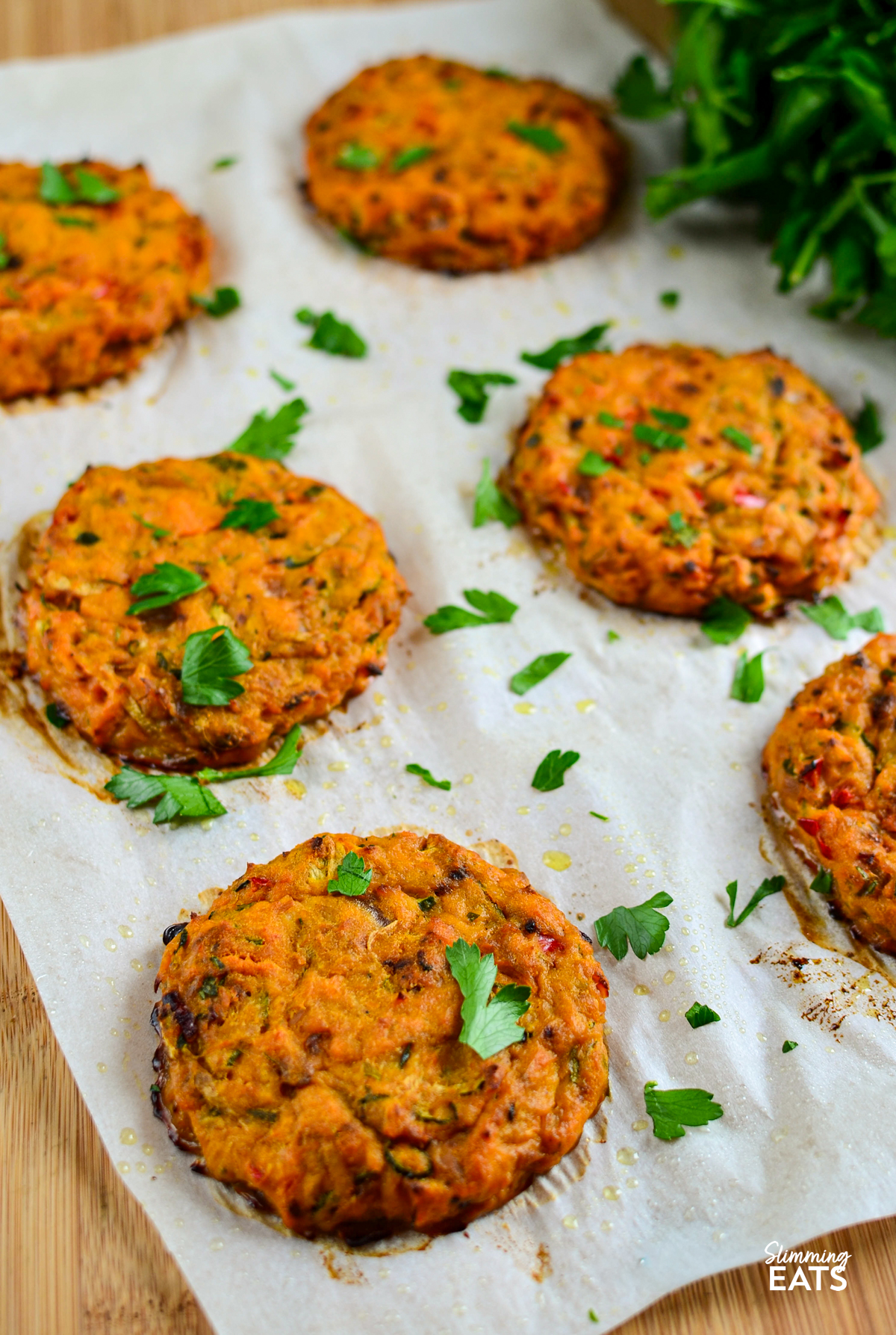 just baked Oven Baked Tuna Sweet Potato Patties on a sheet of parchment paper scattered with fresh parsley