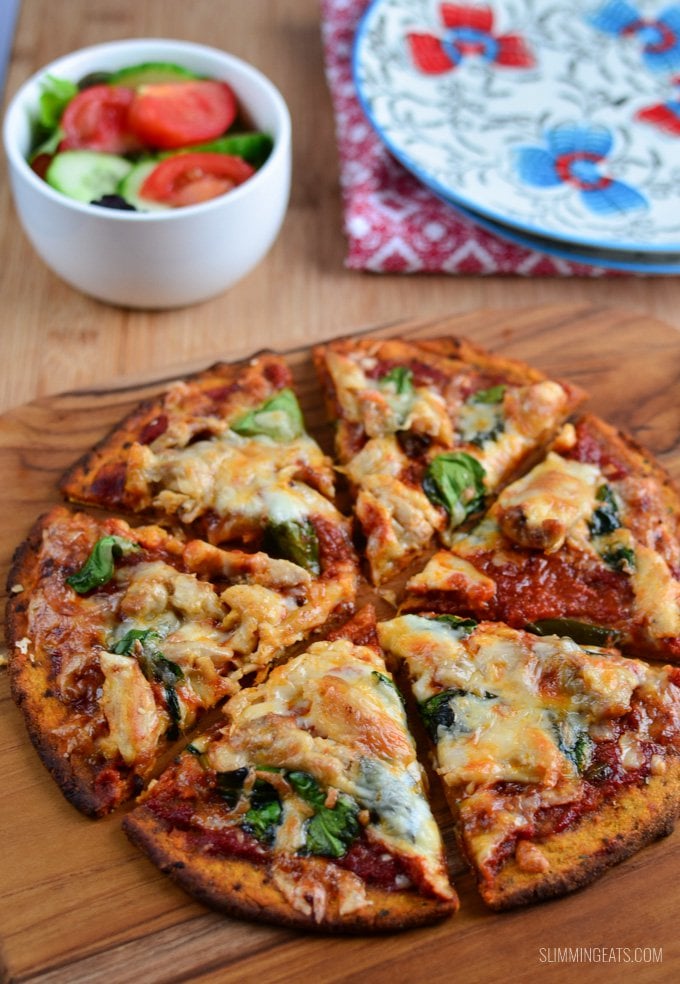 sweet potato pizza base on board with salad in a white bowl