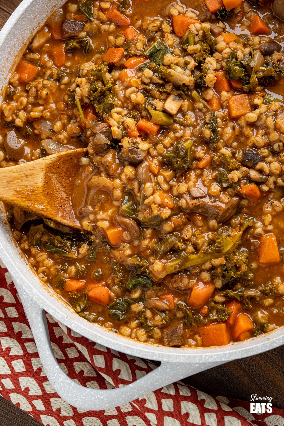 close up of Beef and barley stew in pot with wooden spoon