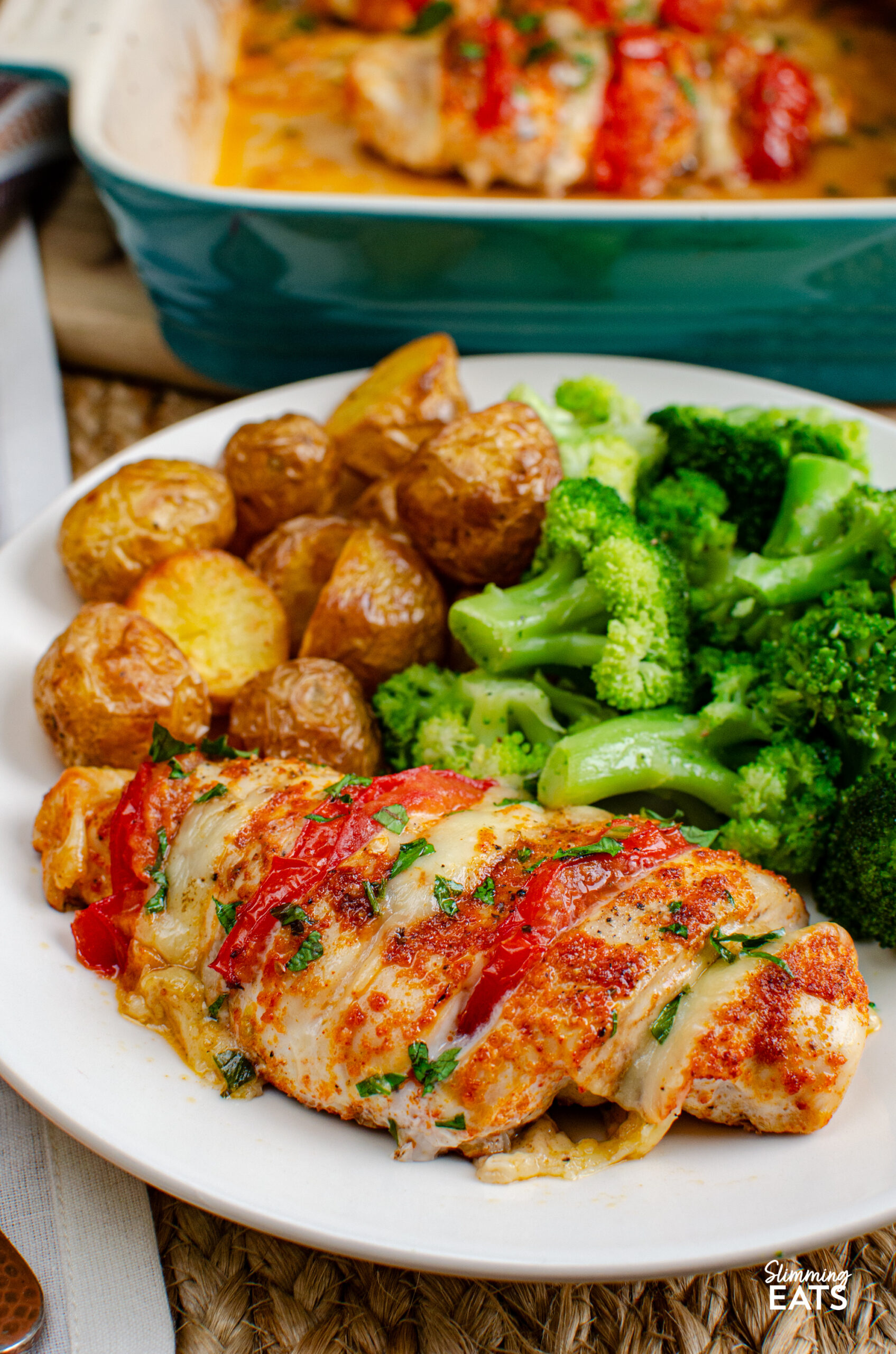 This Tomato Mozzarella Hasselback Chicken turns simple chicken breasts into an easy family dinner with juicy tomato and melted mozzarella. Tomato and mozzarella stuffed hasselback chicken on a white plate with roasted skin on baby potatoes and steamed broccoli