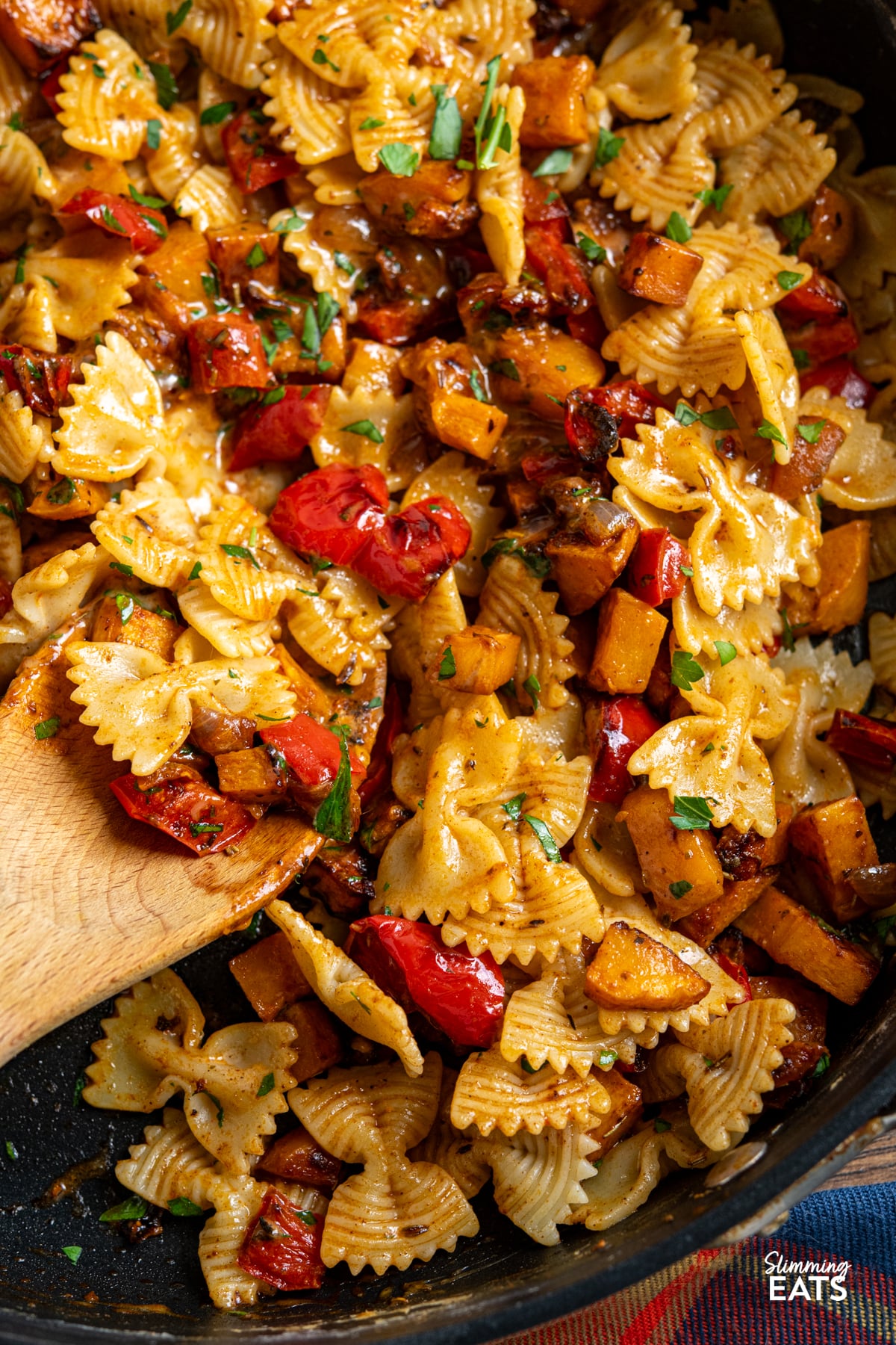 close up of Roasted Butternut Squash and Red Pepper Pasta with Gruyere in a pan with wooden spoon