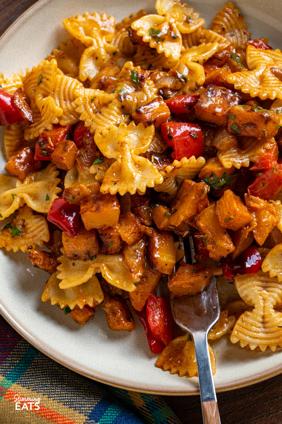 close up of Roasted Butternut Squash and Red Pepper Pasta with Gruyere on white plates with beige rim