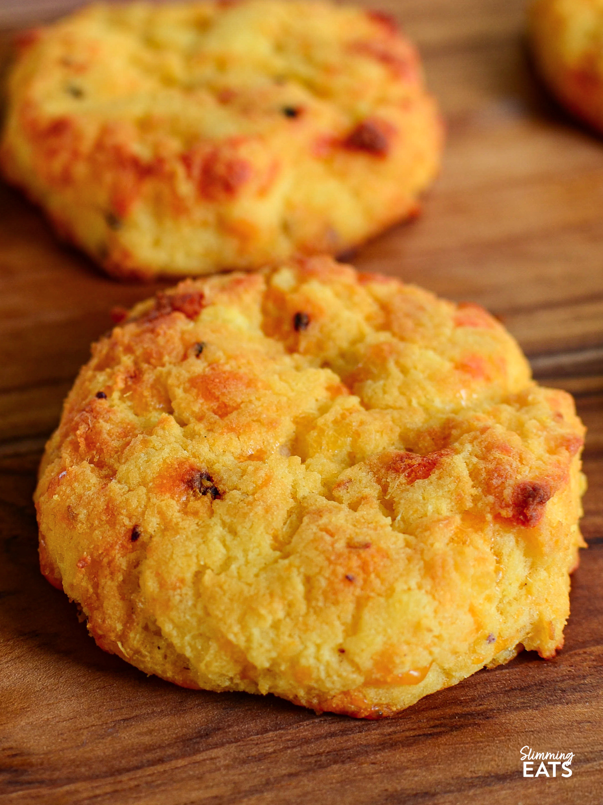 two sweet potato cheddar scones on wooden board fresh out of oven