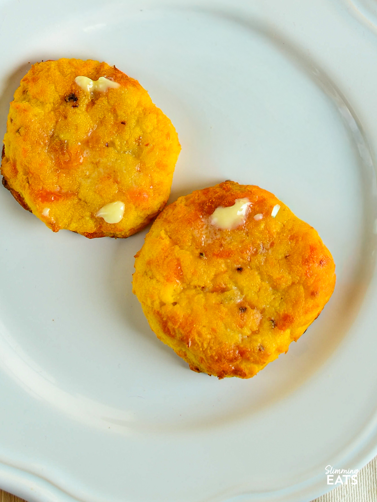 two sweet potato cheddar scones on white plate and spread with butter