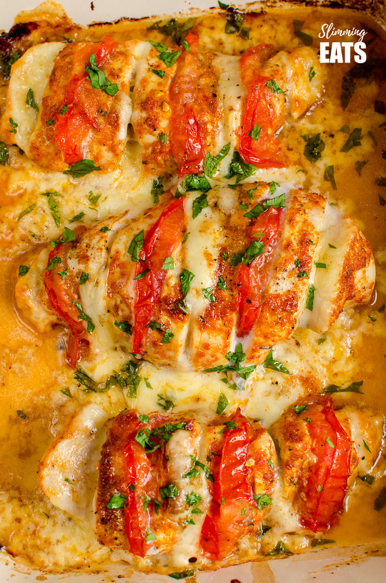 close up of tomato and mozzarella hasselback chicken in ovenproof dish