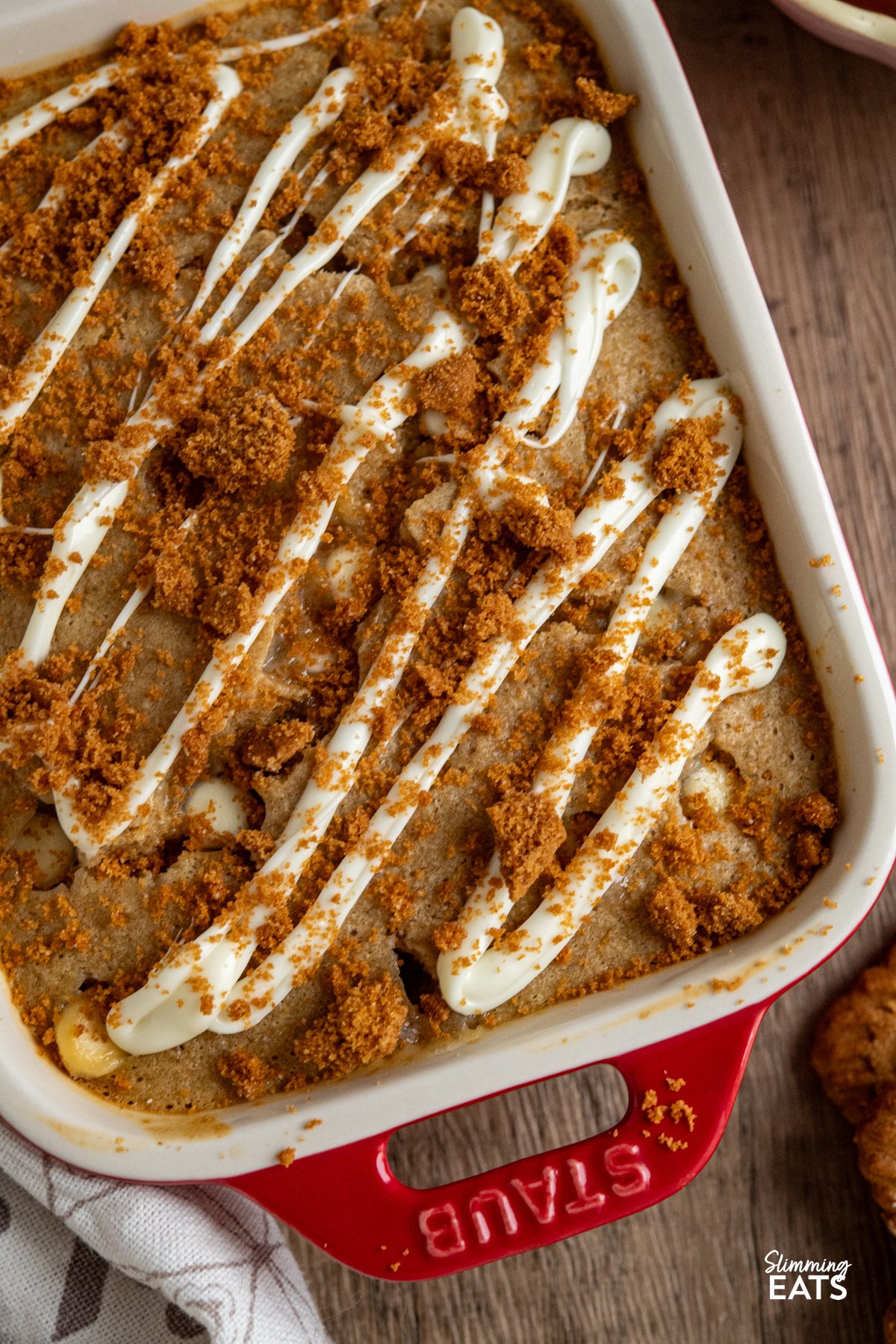 close up of spoon in White Chocolate Chip Oatmeal Cake with Biscoff Cookie Crumb in red mini staub baking dish 