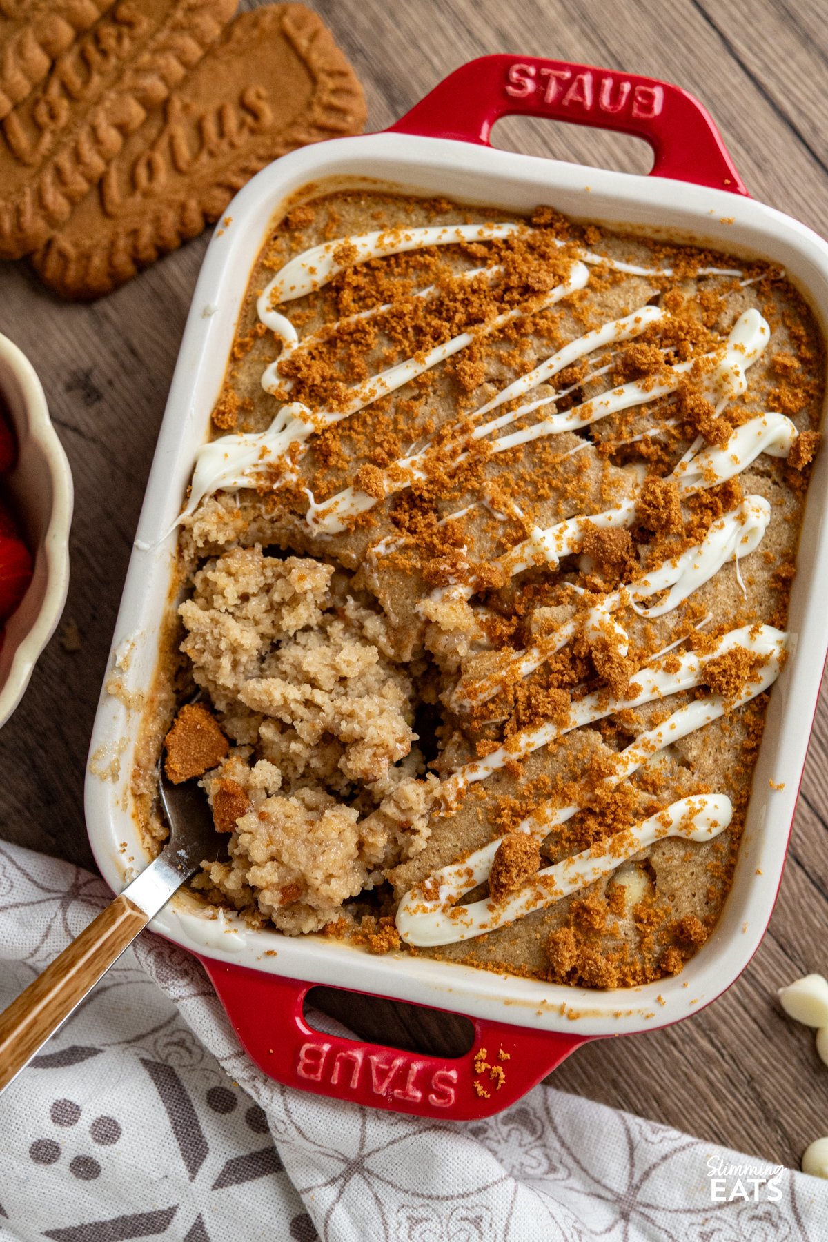 close up of spoon in White Chocolate Chip Oatmeal Cake with Biscoff Cookie Crumb in red mini staub baking dish 