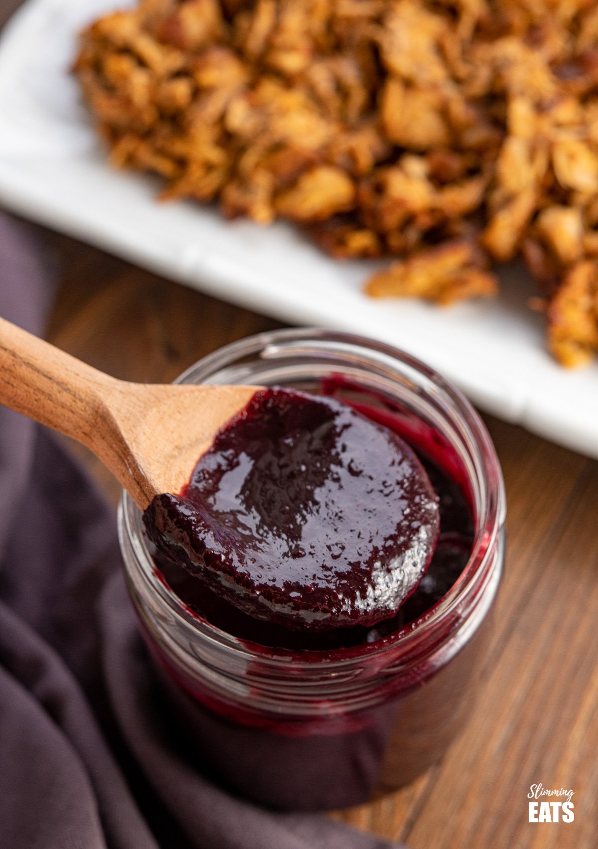 Blueberry bbq sauce in a jar with wooden spoon spooning some out.