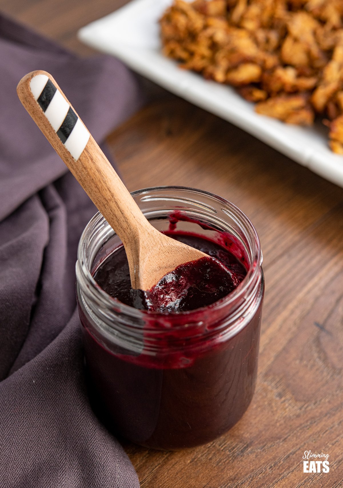 blueberry bbq sauce in jar with wooden spoon with black and white stripes on handle
