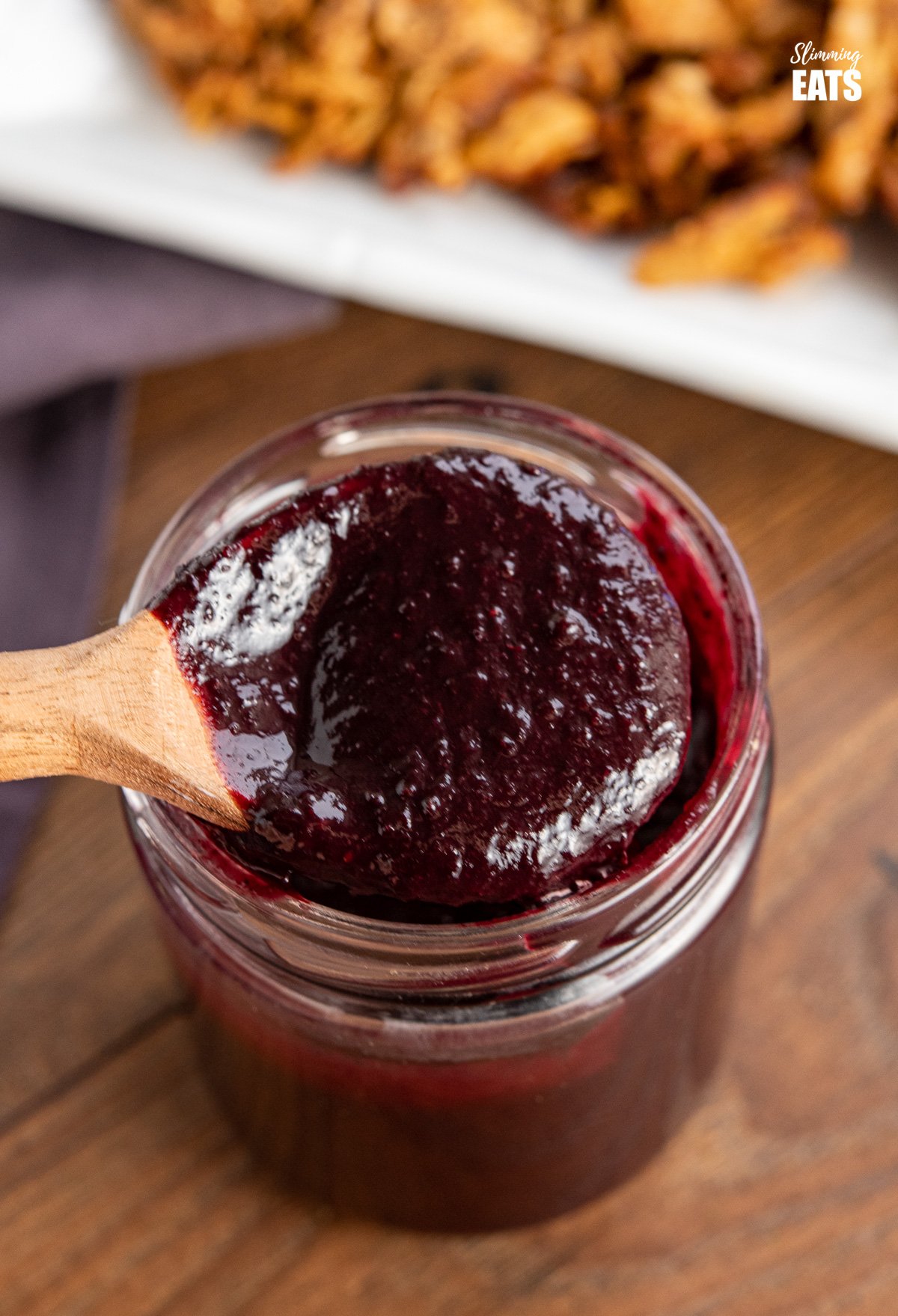 wooden spoon spooning up blueberry bbq sauce from jar