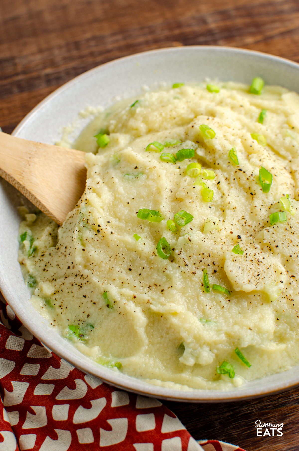 Sour Cream and Spring Onion Cauliflower Mash in a bowl with wooden spoon