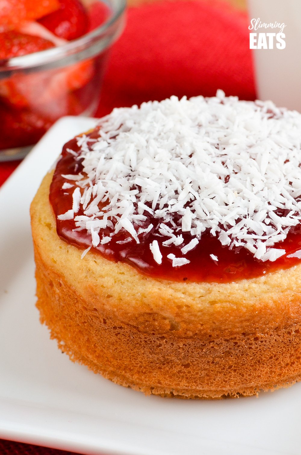 Jam and Coconut Sponge Cake - a delicious journey back to childhood with this oat based coconut sponge, topped with sweet jam and shredded coconut. A perfect filling start to your day. Gluten Free, Vegetarian, Slimming and Weight Watchers friendly close up of Jam and Coconut Sponge Cake on white plate