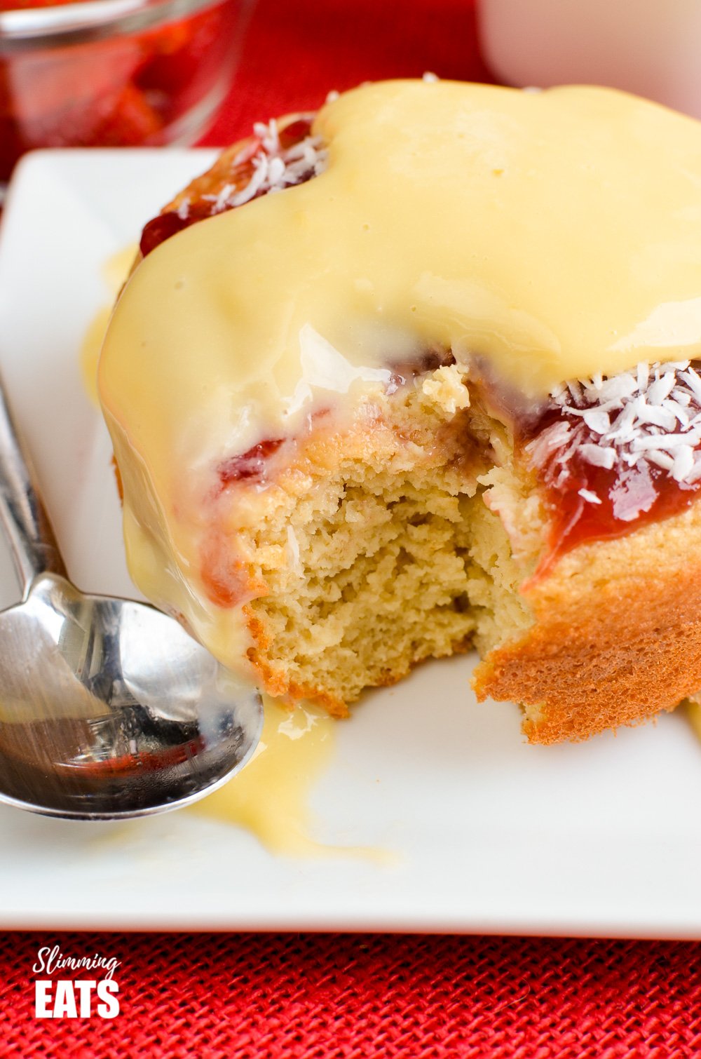 Jam and Coconut Sponge Cake - a delicious journey back to childhood with this oat based coconut sponge, topped with sweet jam and shredded coconut. A perfect filling start to your day. Gluten Free, Vegetarian, Slimming and Weight Watchers friendly part eaten jam and coconut sponge cake on white plate