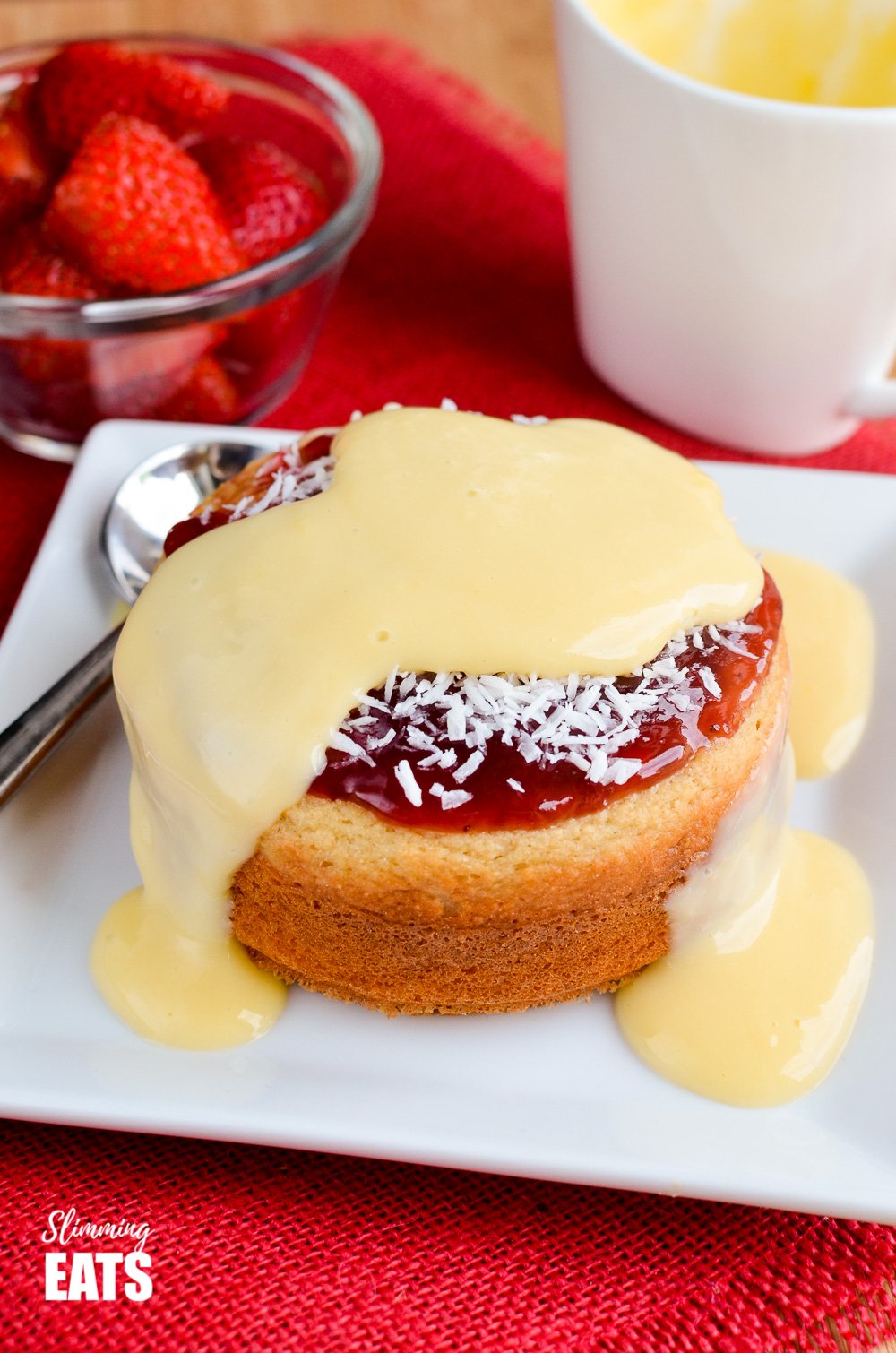 custard over jam and coconut sponge cake on white plate