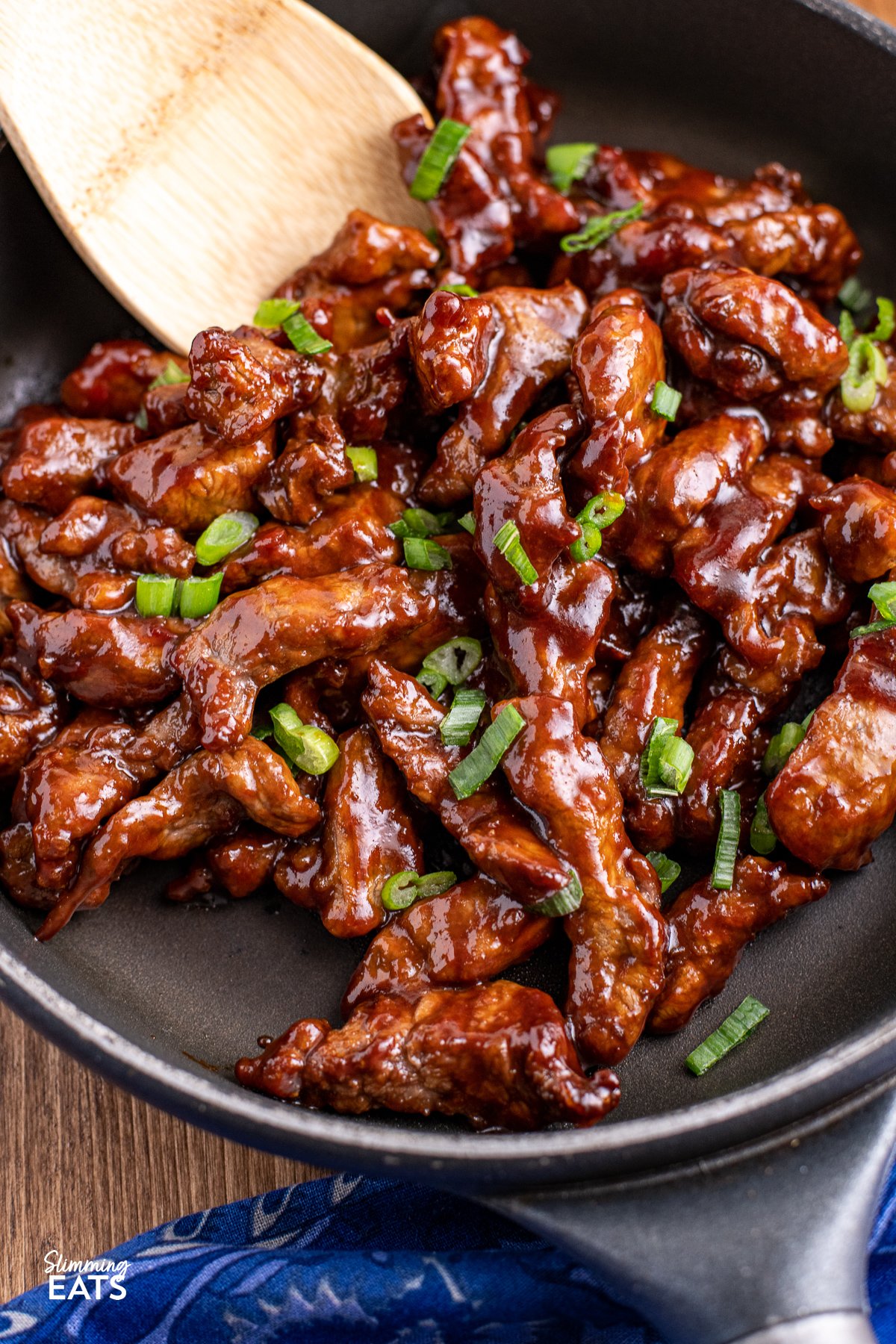 close up of Sweet Chilli Beef in a black frying pan with wooden handle.