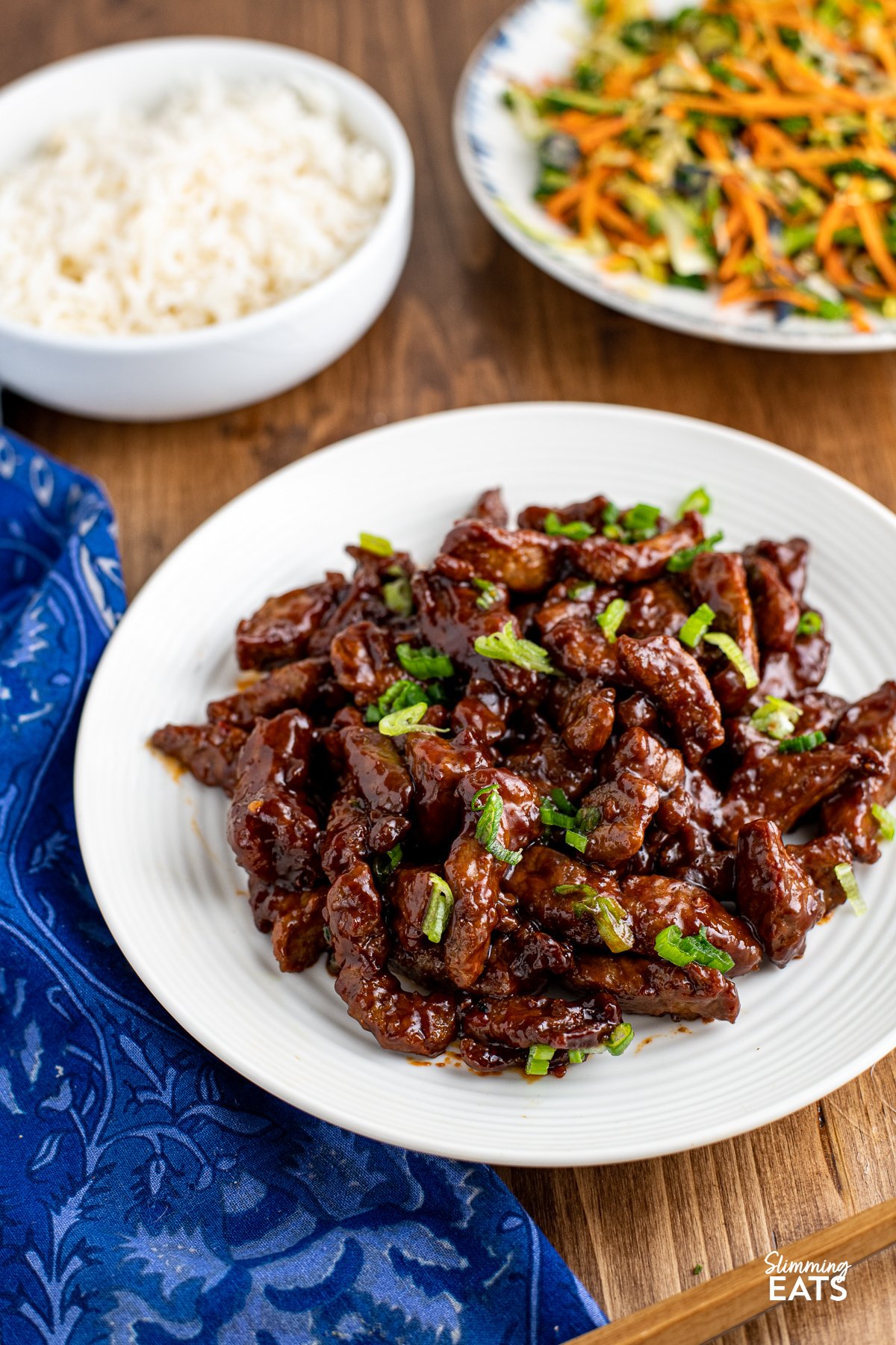 Sweet Chilli Beef on a white plate, sprinkled with spring onions